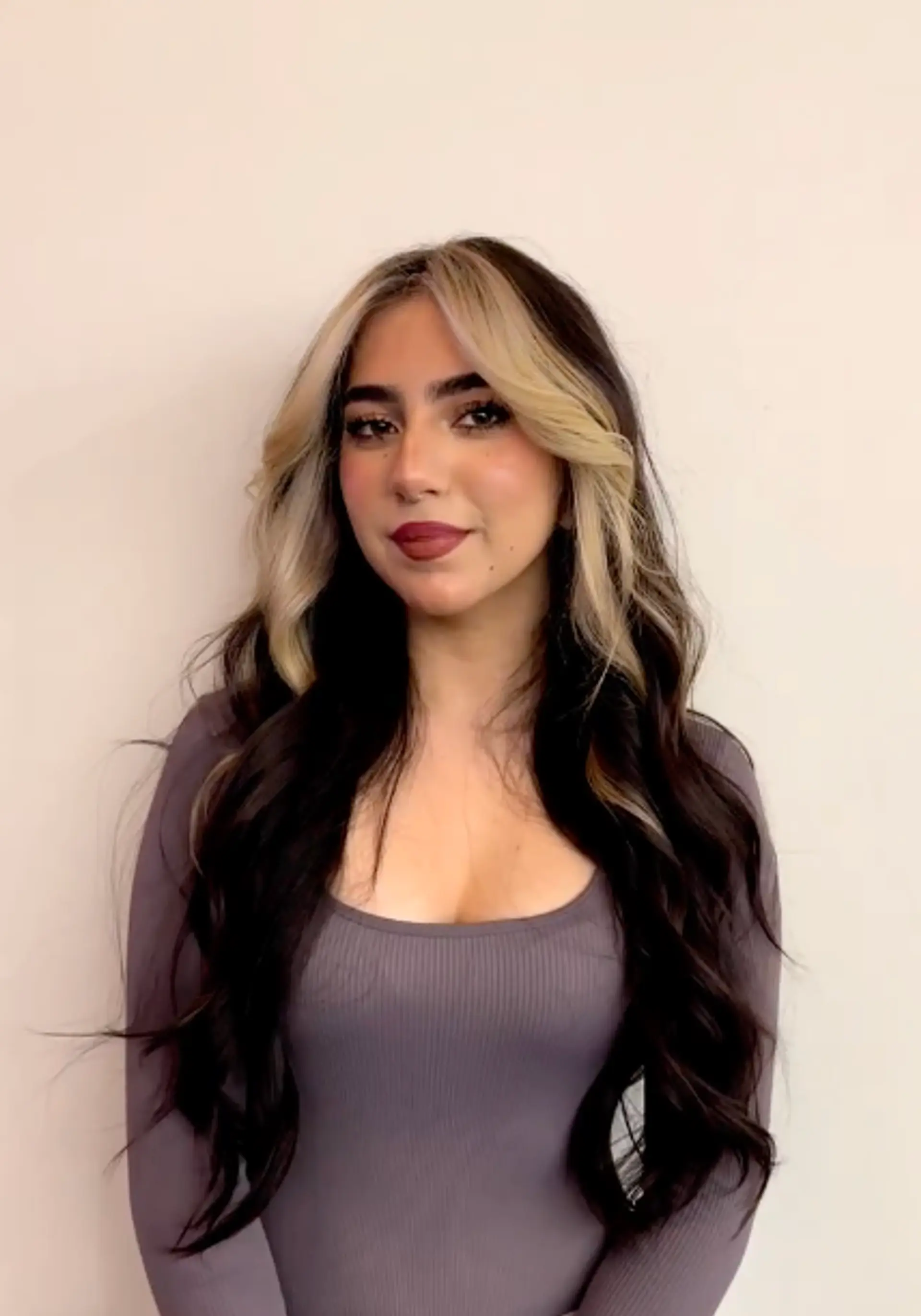 Long wavy hair with blonde money piece highlights framing the face. 1