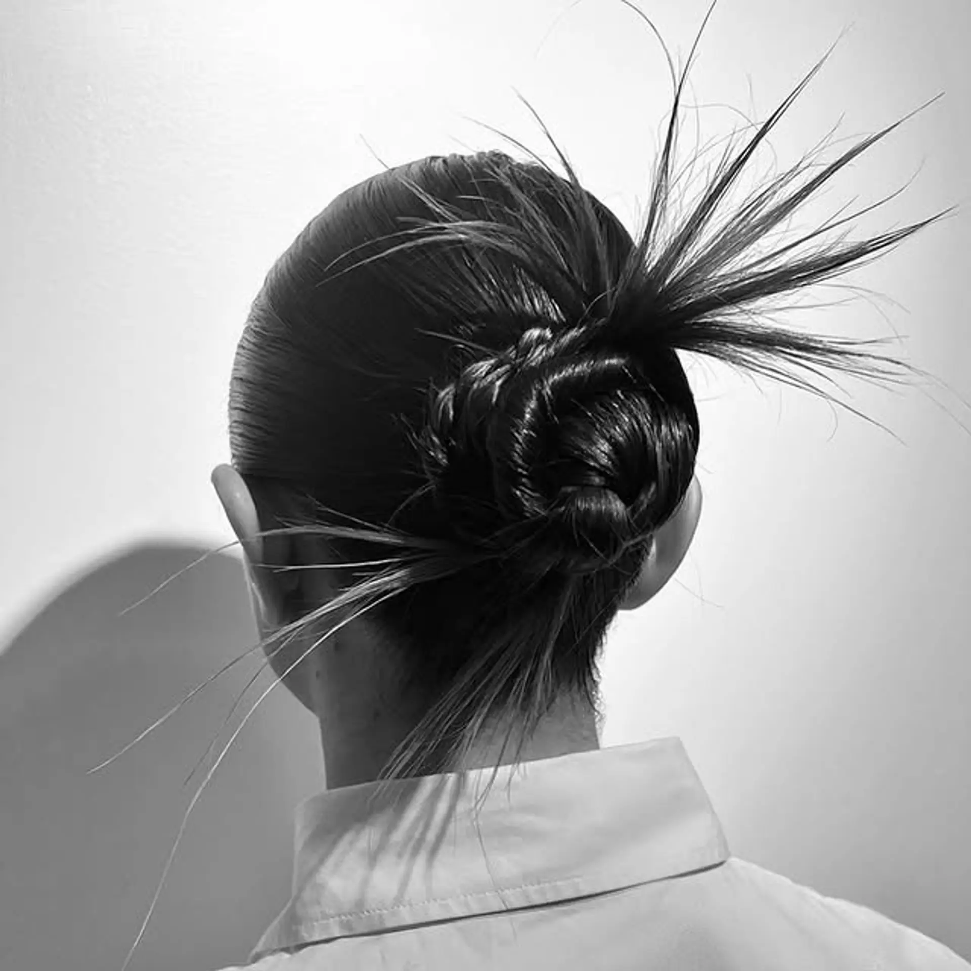 A sleek updo with a braided base that transitions into a stylish top knot. The addition of spiky strands adds a unique, edgy touch. 1