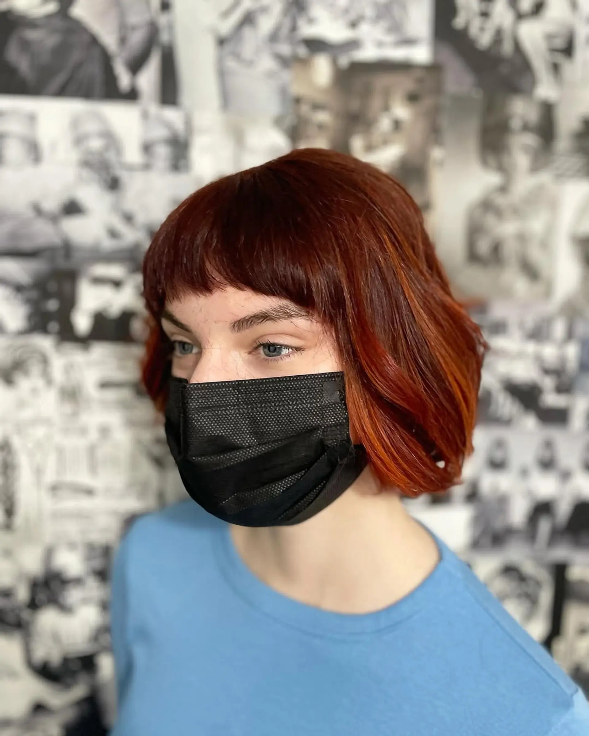 A short, textured bob hairstyle characterized by its rich auburn red base color, artfully enhanced with bright copper and orange dimensional highlights. The hair is styled with soft waves, providing volume and a contemporary finish. 2