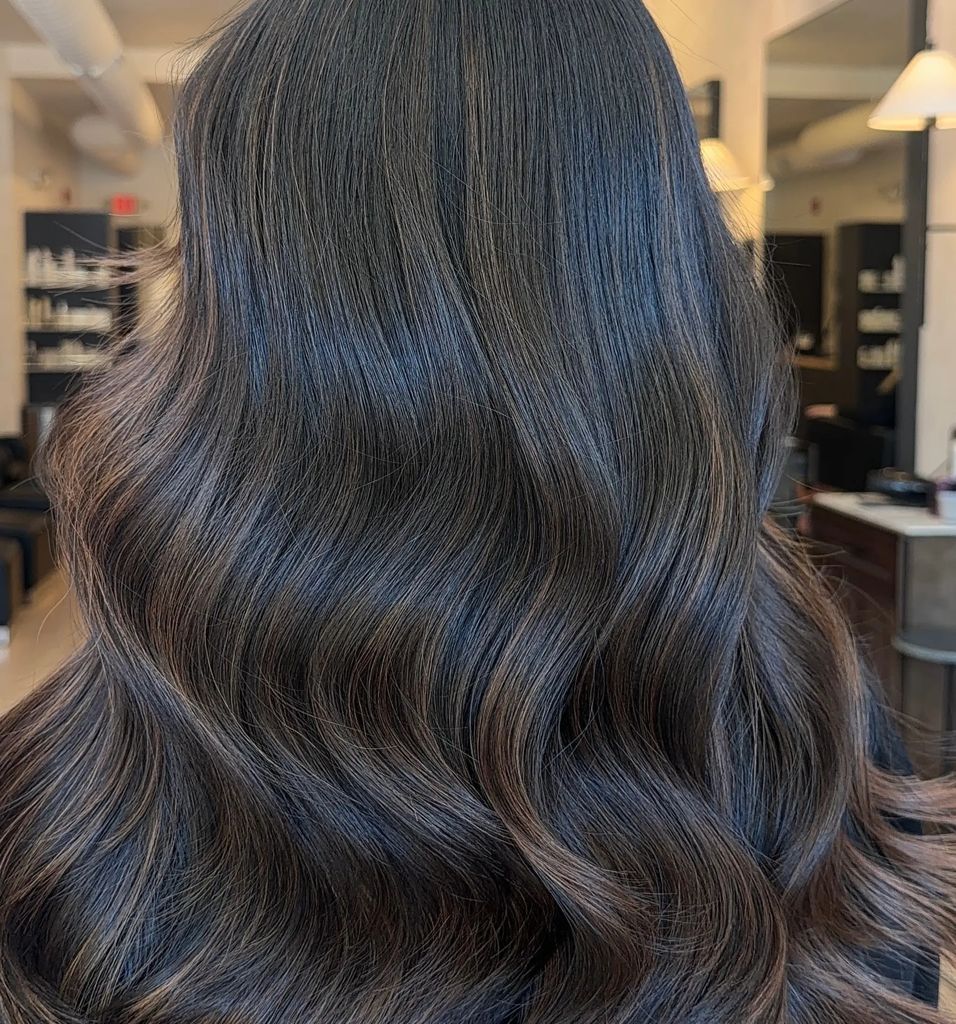 Long dark brunette hair styled into smooth, flowing waves with subtle warm dimensional highlights. 1