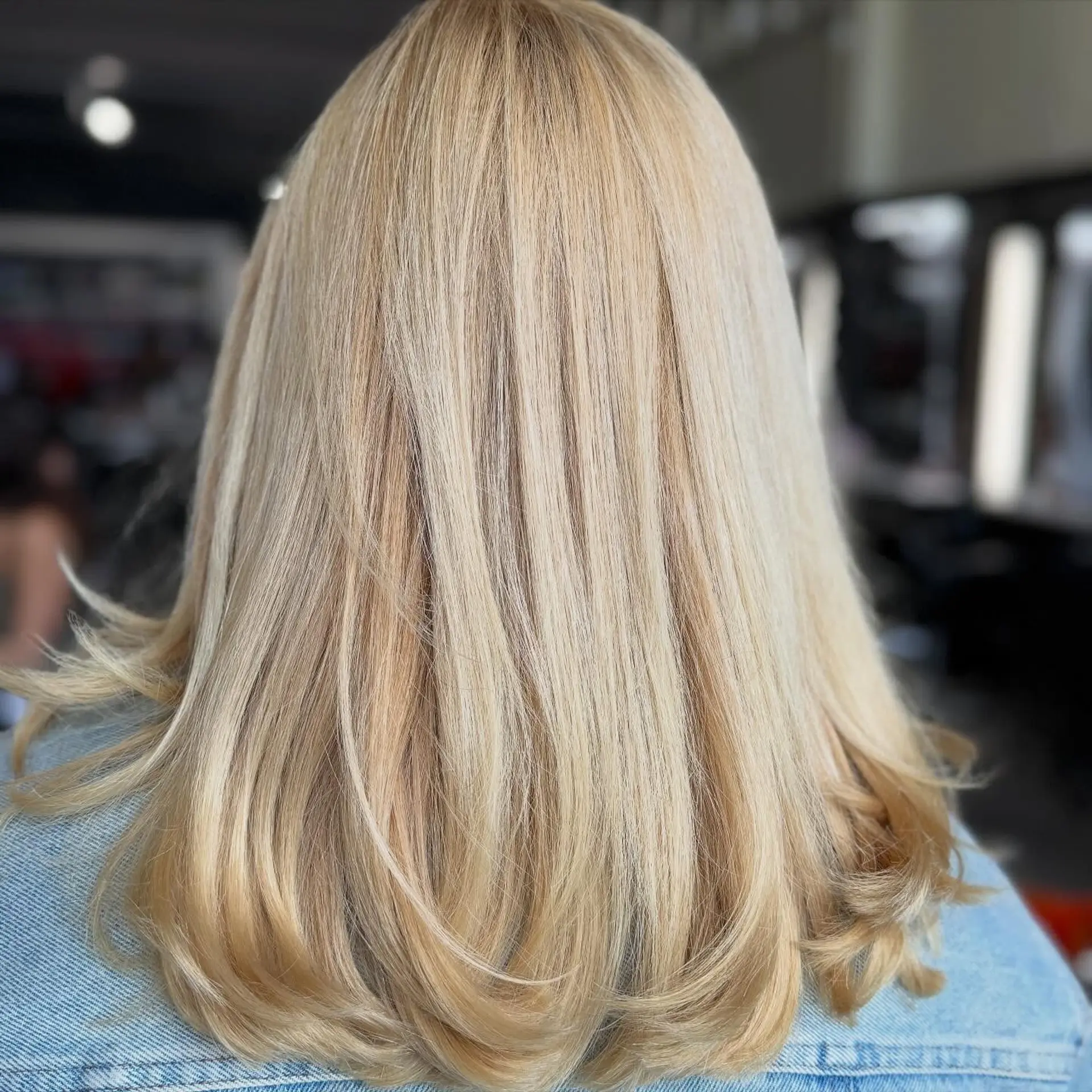 Medium-length golden blonde hair styled with a voluminous, smooth blowout and gently curled-under ends. 1