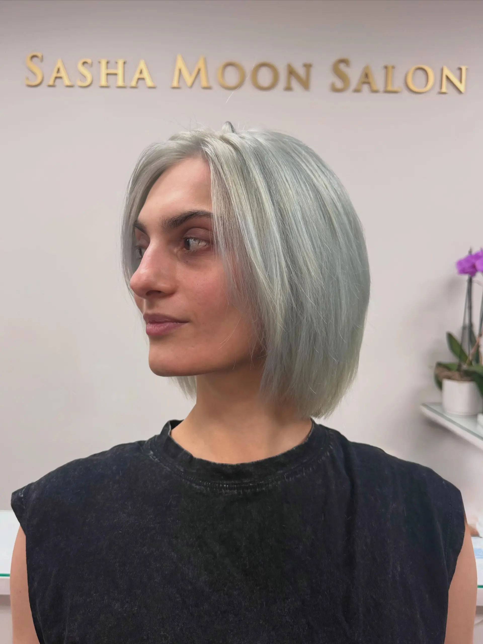 A sleek, chin-length bob with shattered layers colored in a cool, icy blue-steel platinum blonde. 1