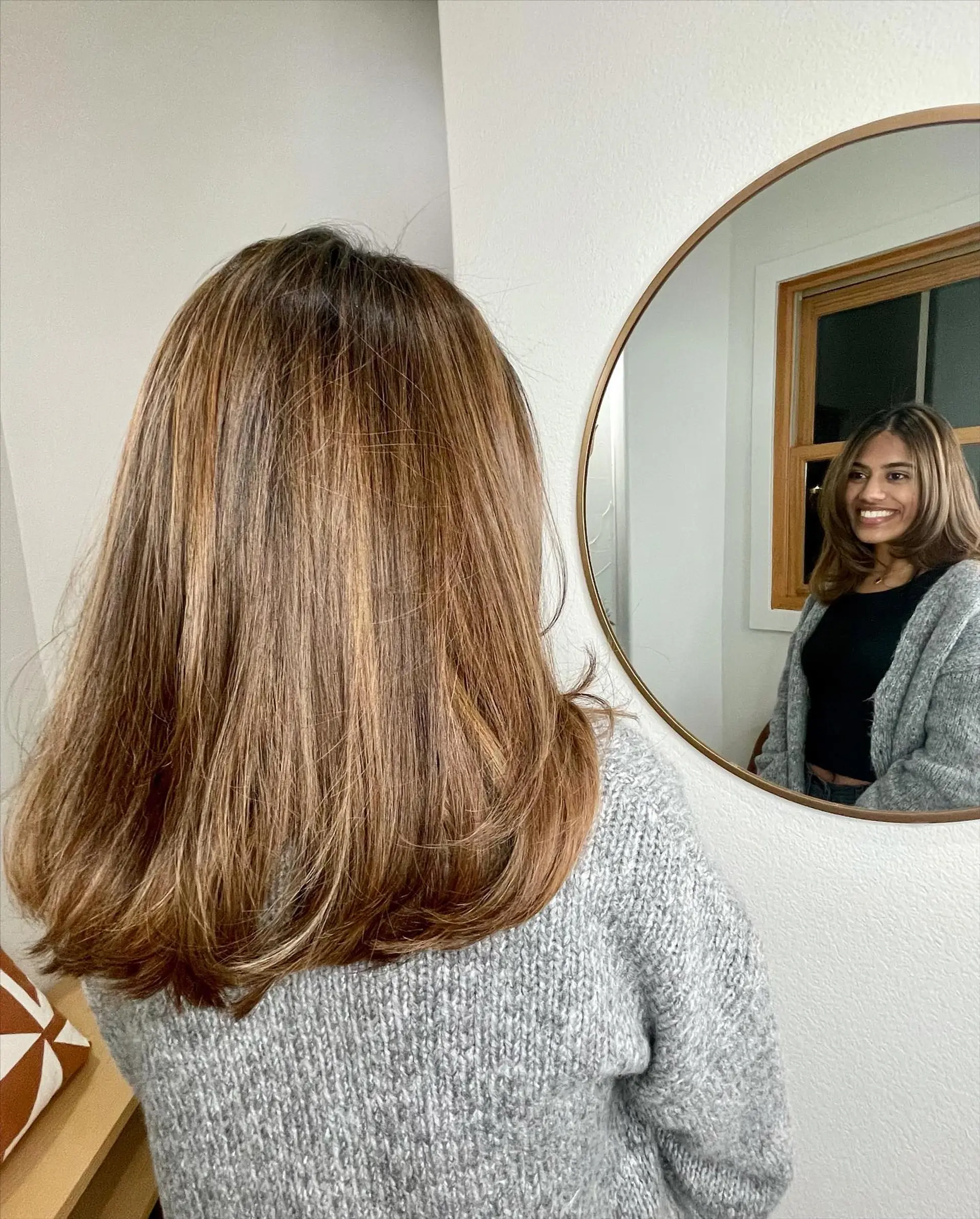 Shoulder-length layered hair styled in a smooth blowout with softly curved ends, featuring warm golden caramel tones blended into a brunette base. 1