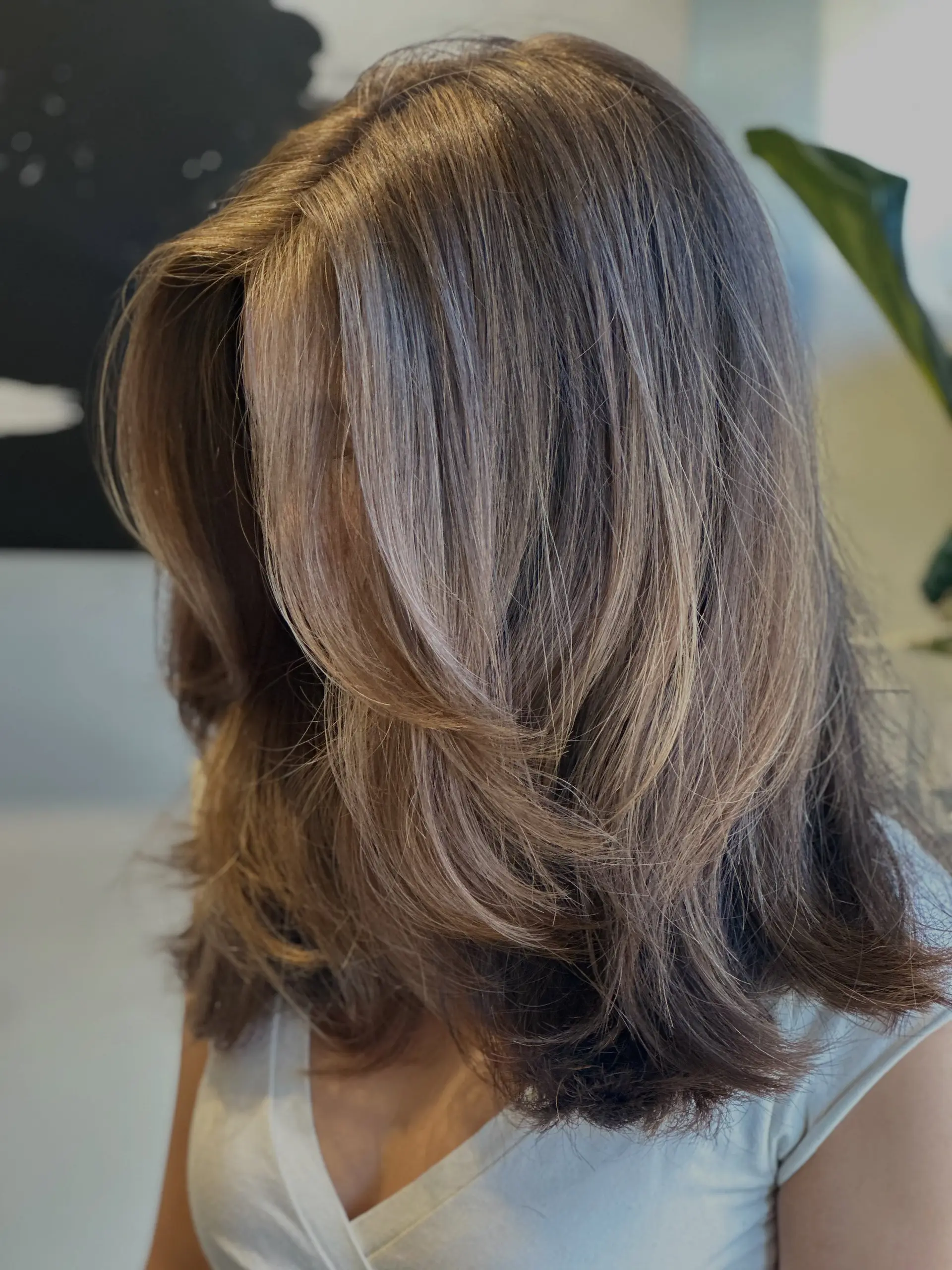 Medium-length haircut featuring face-framing long layers and soft, dimensional highlights styled with a bouncy blowout. 1