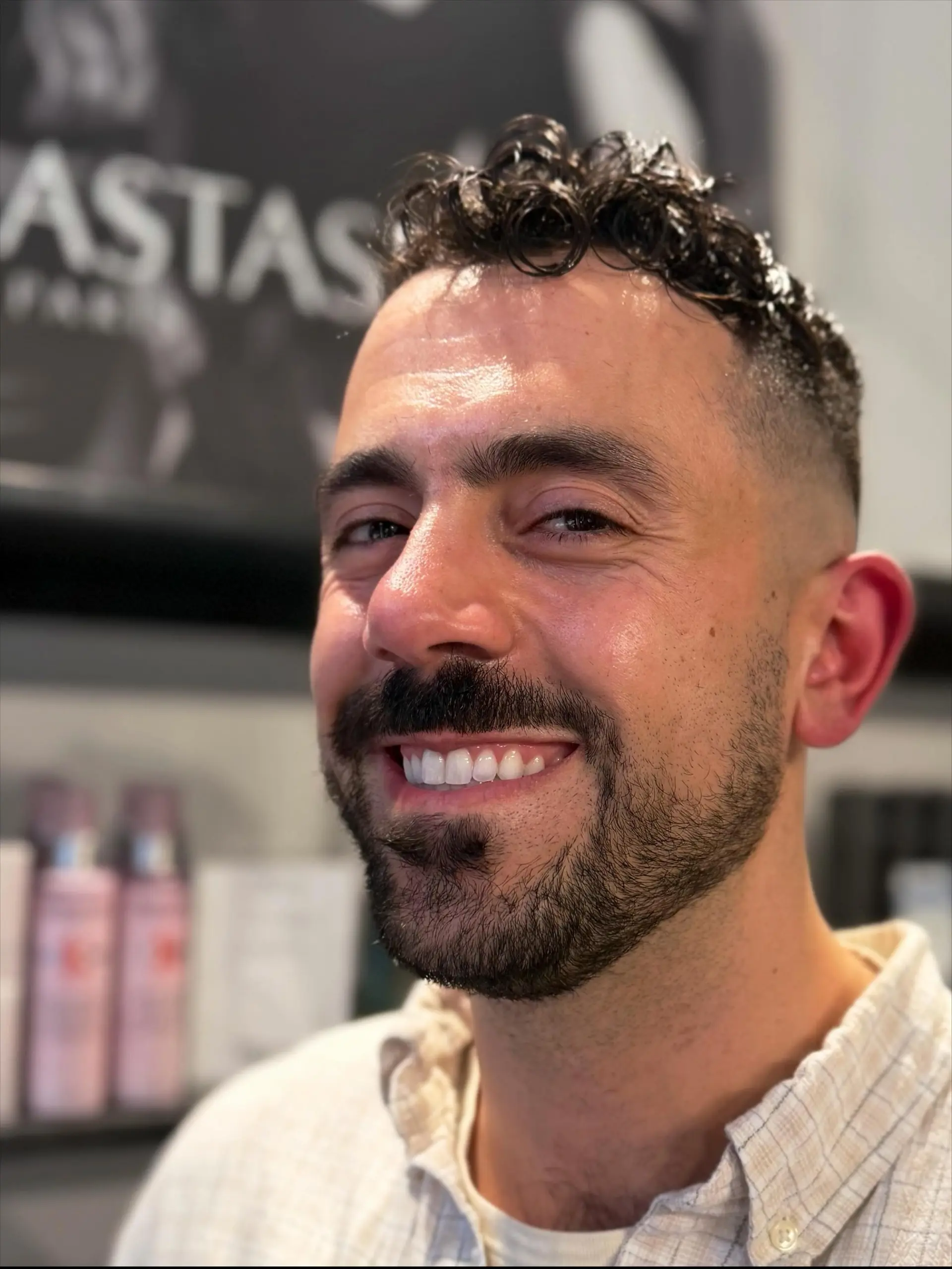 A men's short haircut featuring a clean fade on the sides with textured, defined curls on top. 1