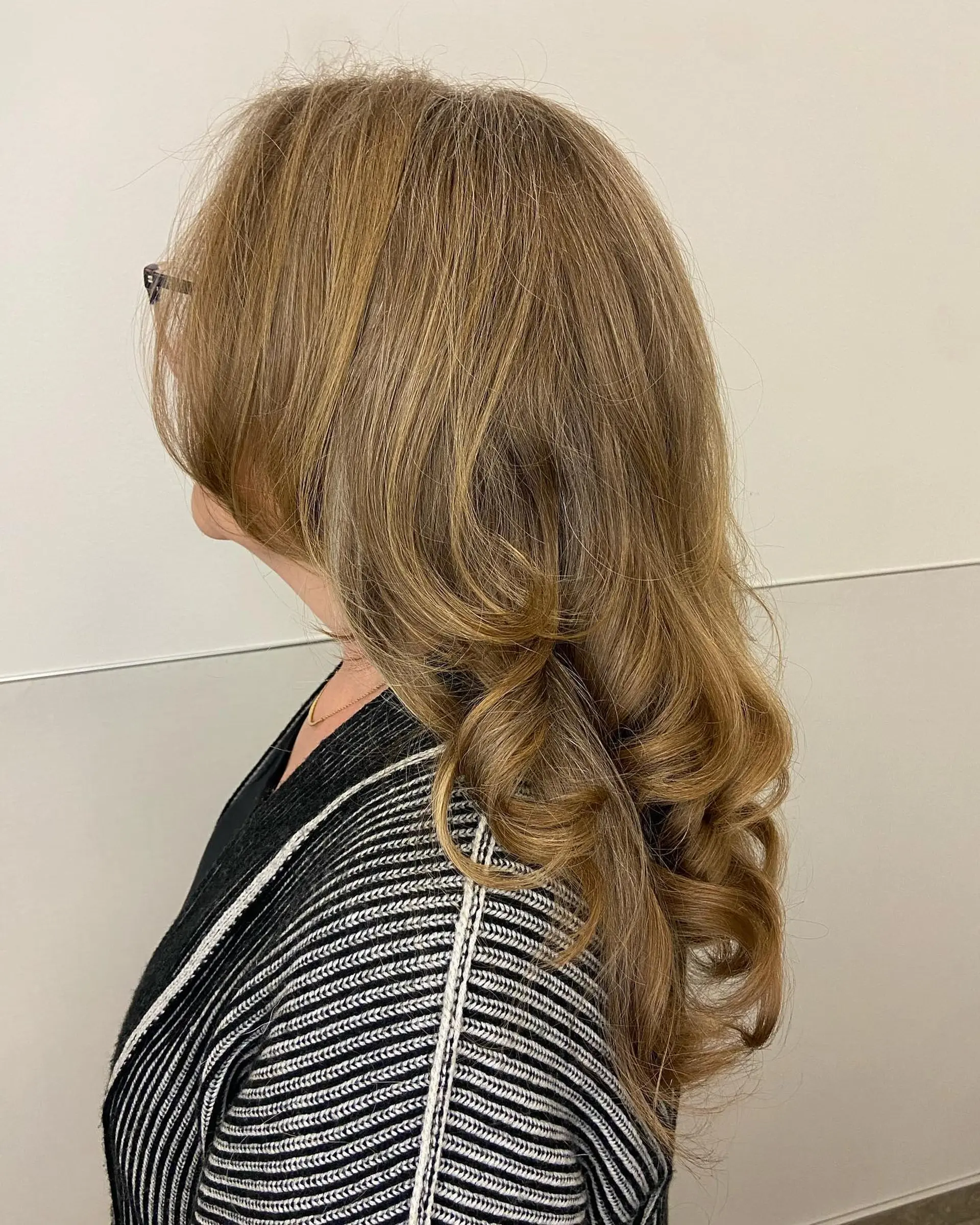 Long cascading layers cut to add dimension, volume, and movement, styled with smooth roots and bouncy spiral curls concentrated at the ends. 1