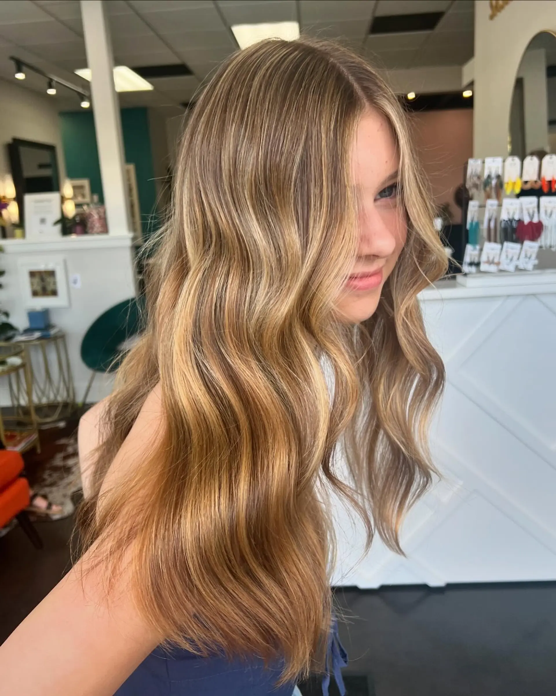 Long, flowing hair styled in loose beach waves with warm, natural golden blonde highlights blended over a soft light brown base. 1