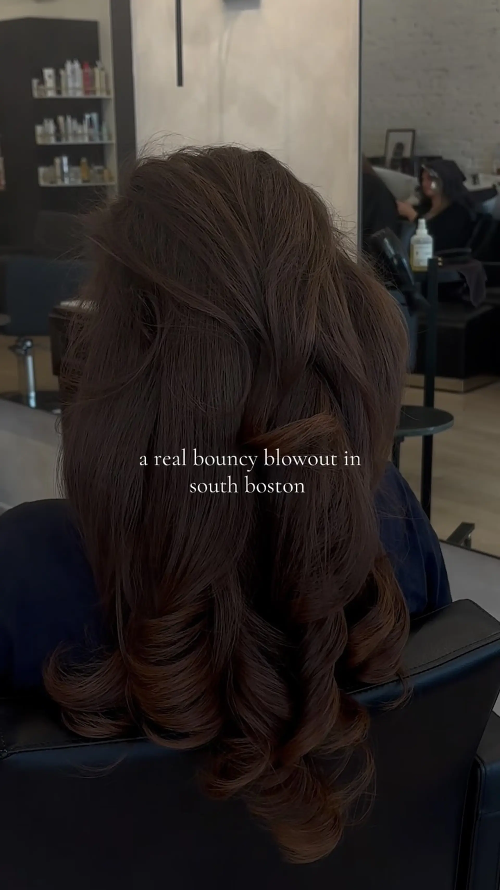 A full, voluminous blowout on rich dark brown hair featuring smooth mid-lengths and defined, bouncy curls at the ends. 1