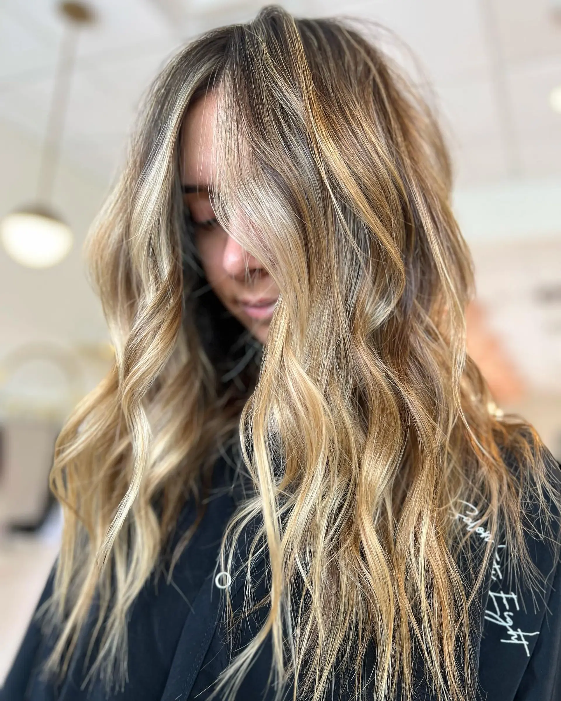Long dimensional golden blonde balayage styled with textured, effortless waves. 1