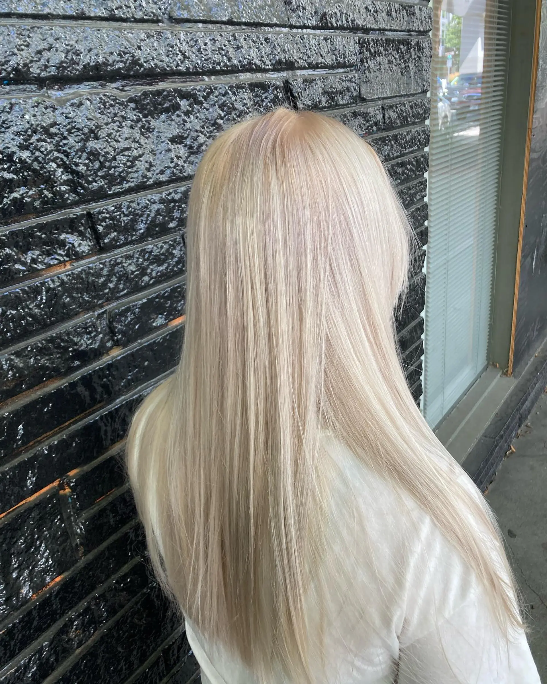 Long, pin-straight hair in an all-over cool platinum blonde tone with a smooth, glossy finish. 1