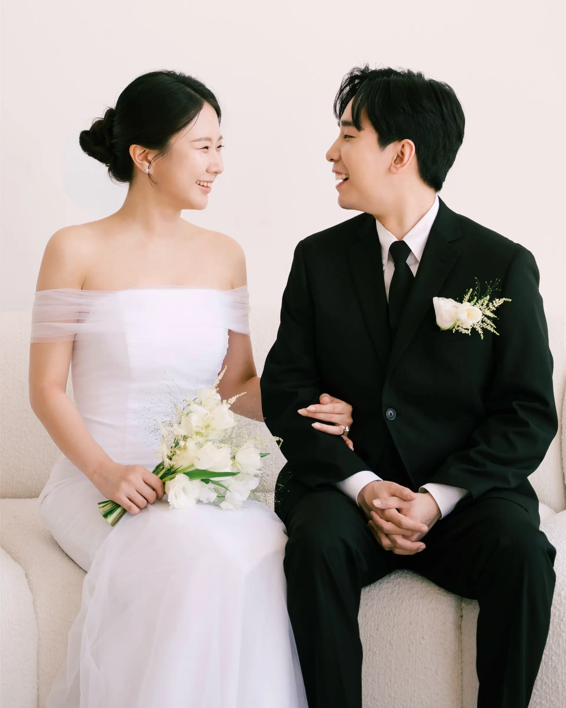 A sleek bridal low chignon updo paired with a softly parted, naturally styled groom haircut. 1