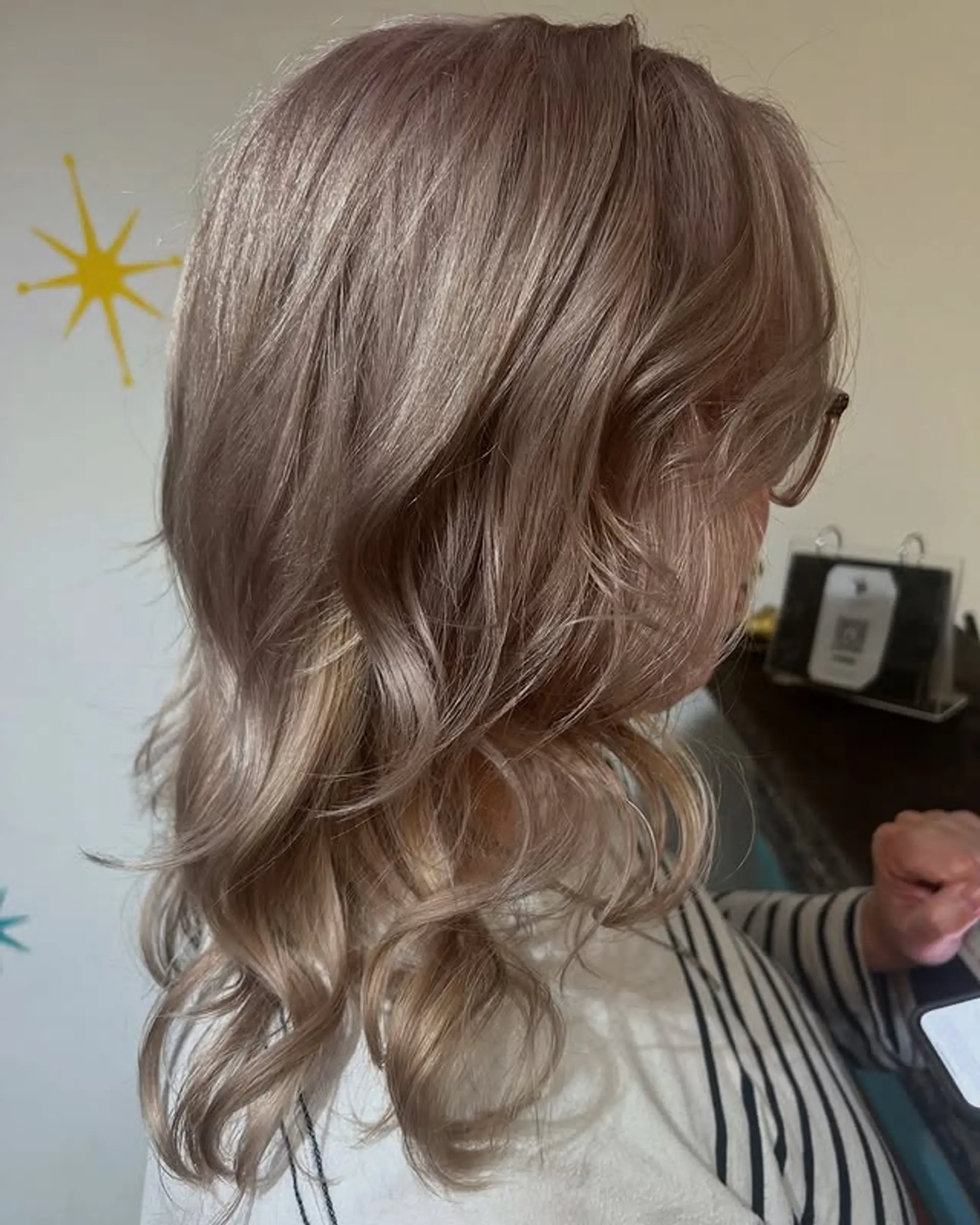 A medium length layered haircut with soft waves and an ash blonde toner. 1