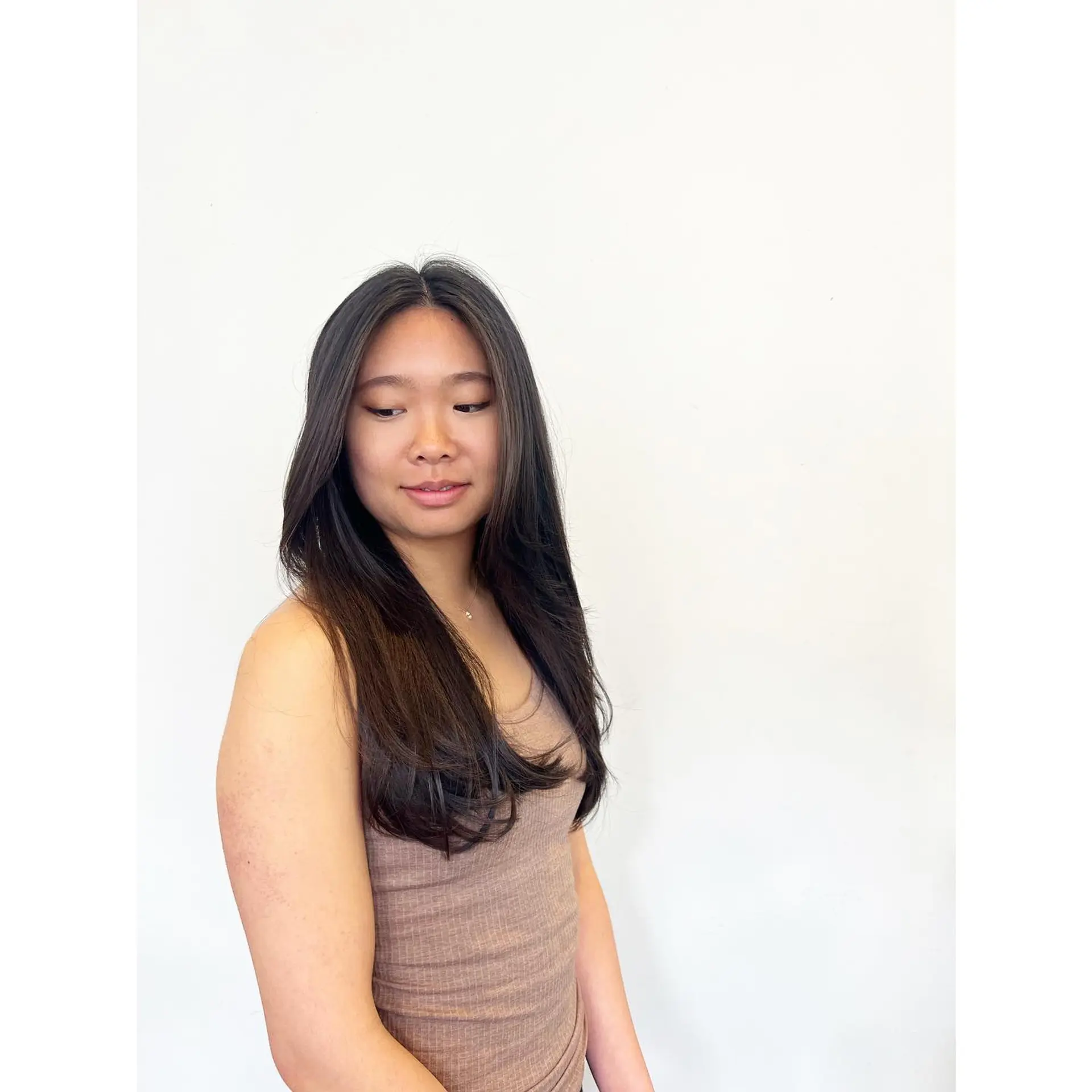 Long, dark hair cut with soft cascading layers and face-framing strands styled smooth with rounded ends. 1