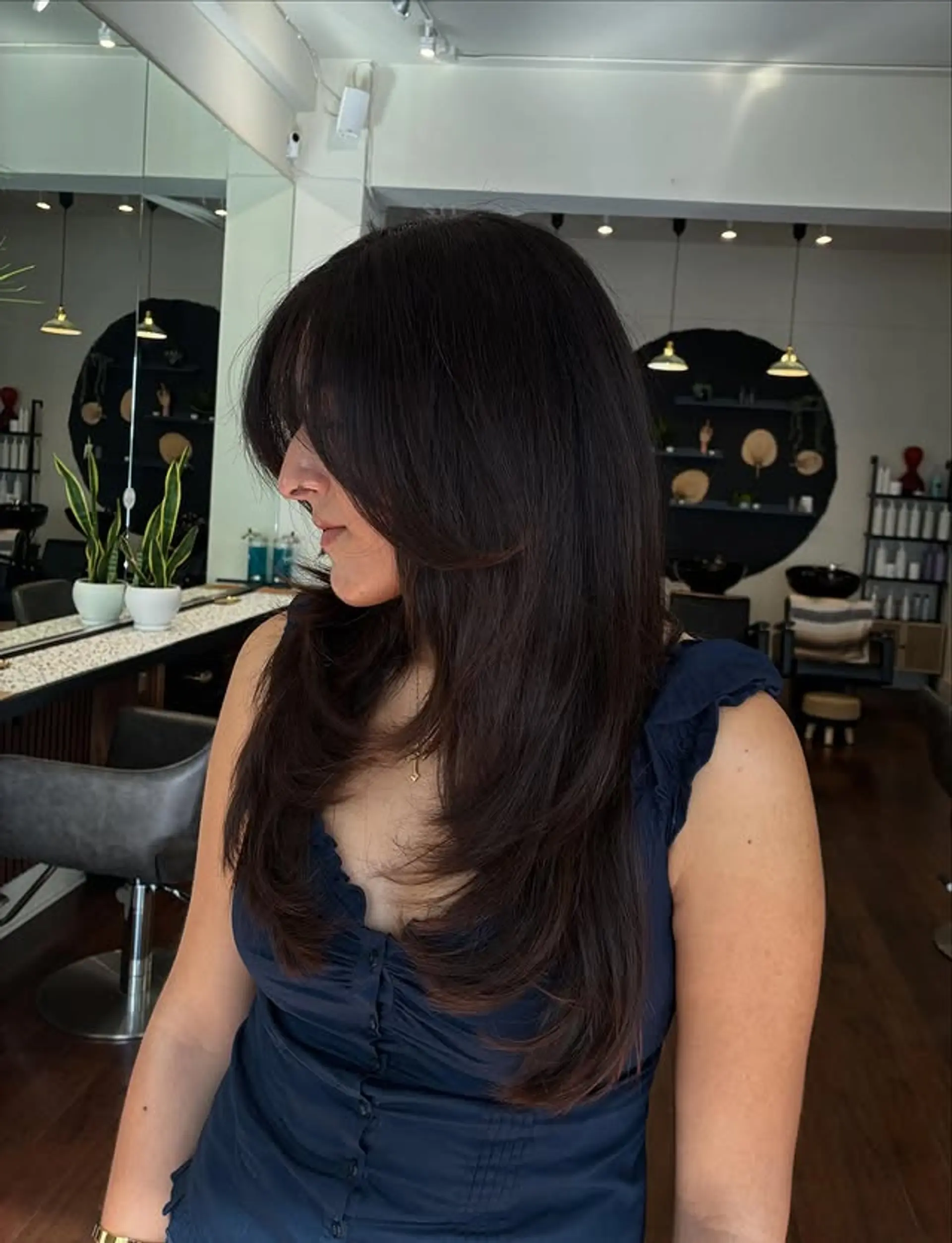 A layered medium-length hairstyle with curtain bangs and soft layers throughout. 1