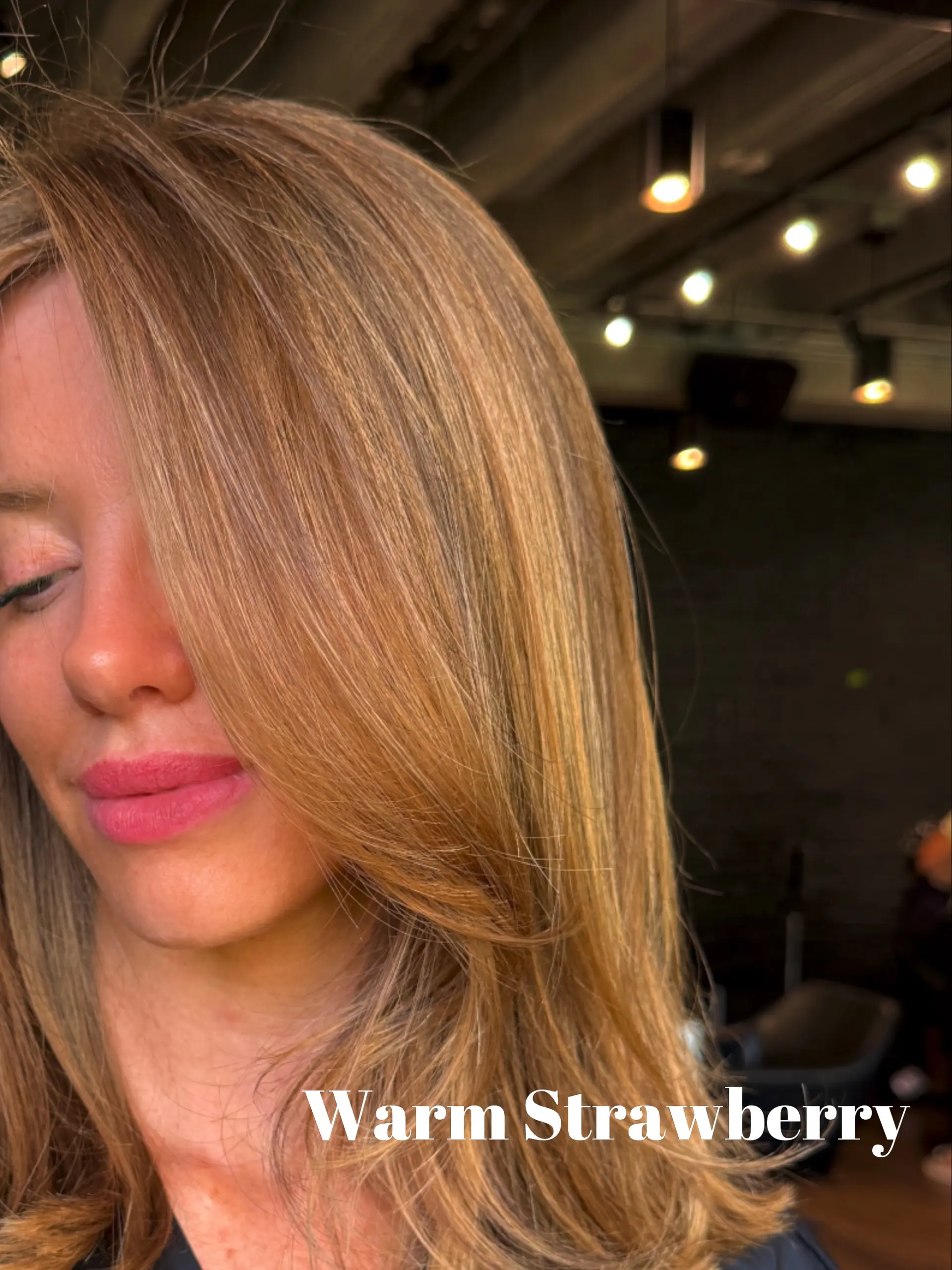 Medium-length warm strawberry blonde hair cut with face-framing layers and styled with a smooth, side-swept fringe. 1
