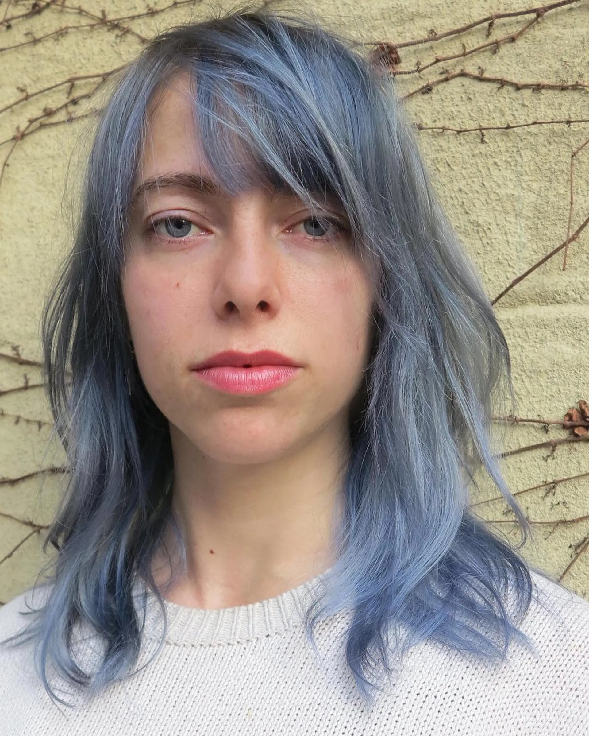 Medium-length wavy hair with a muted blue hue, featuring side bangs and layered texture for a chic look. 1