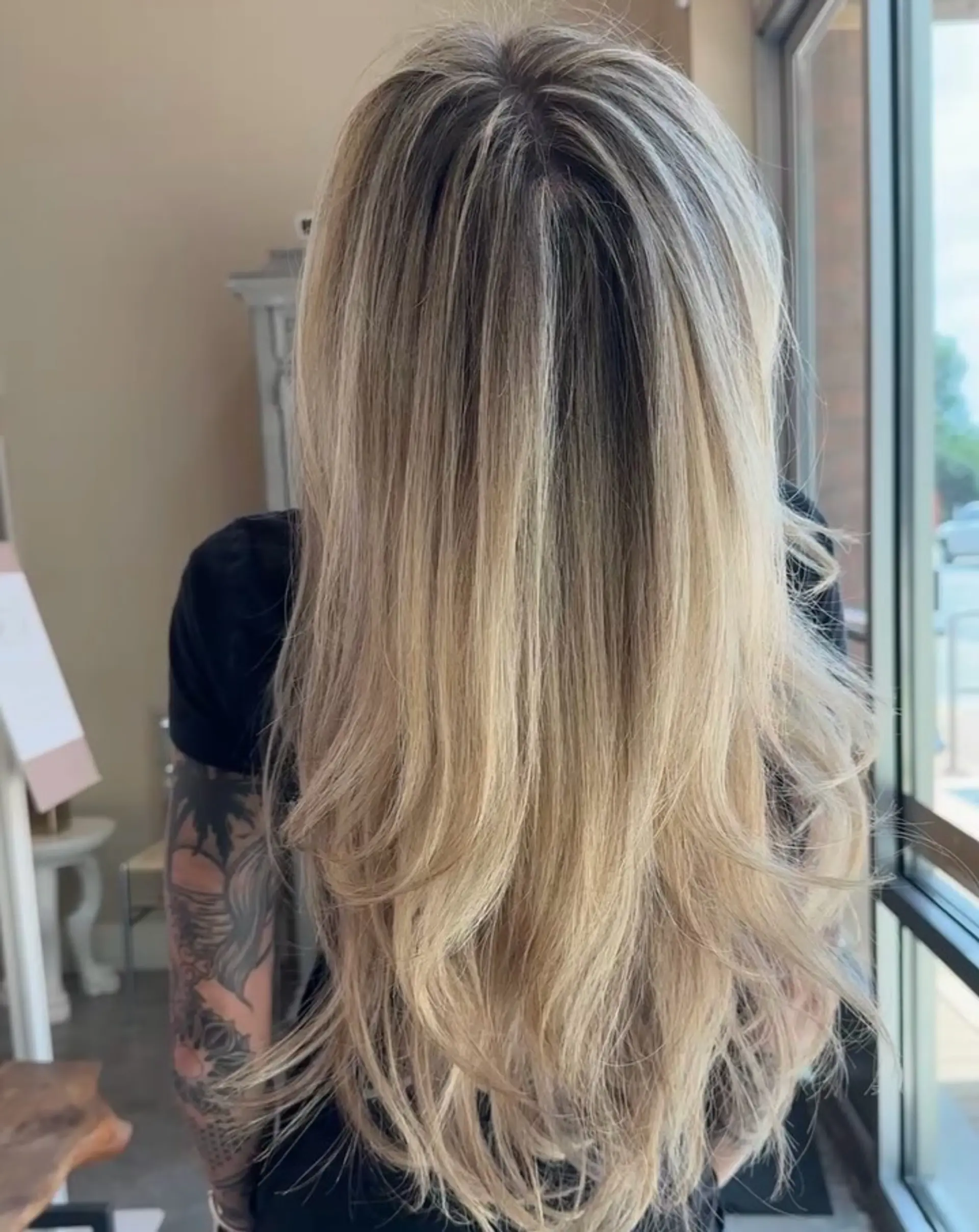 Long multi-dimensional blonde hair with seamless blended highlights, styled in soft layers with a smooth blowout finish. 1
