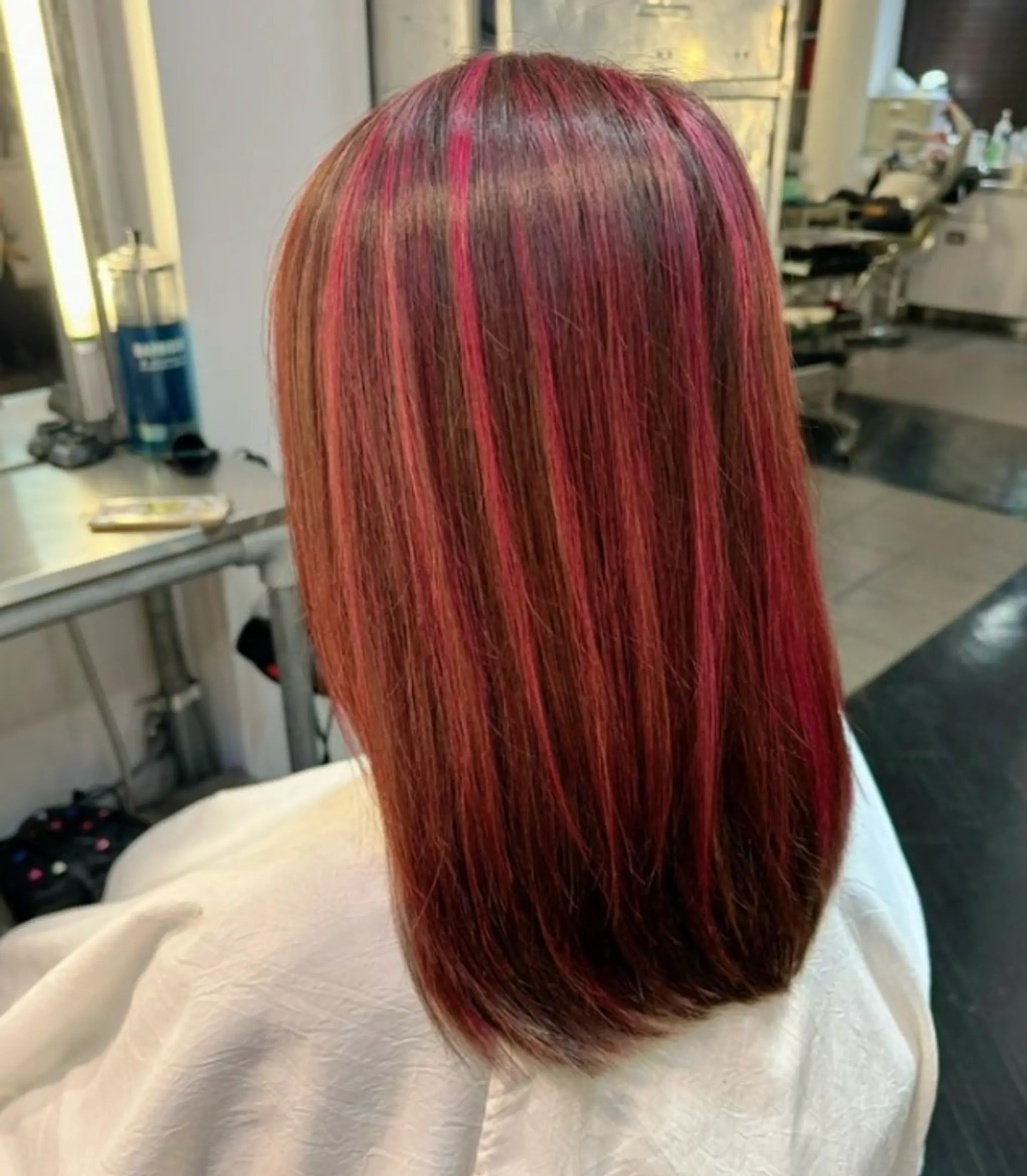 Sleek, straight medium length hair with a rich brown base and vibrant red highlights, featuring an ombre effect.

