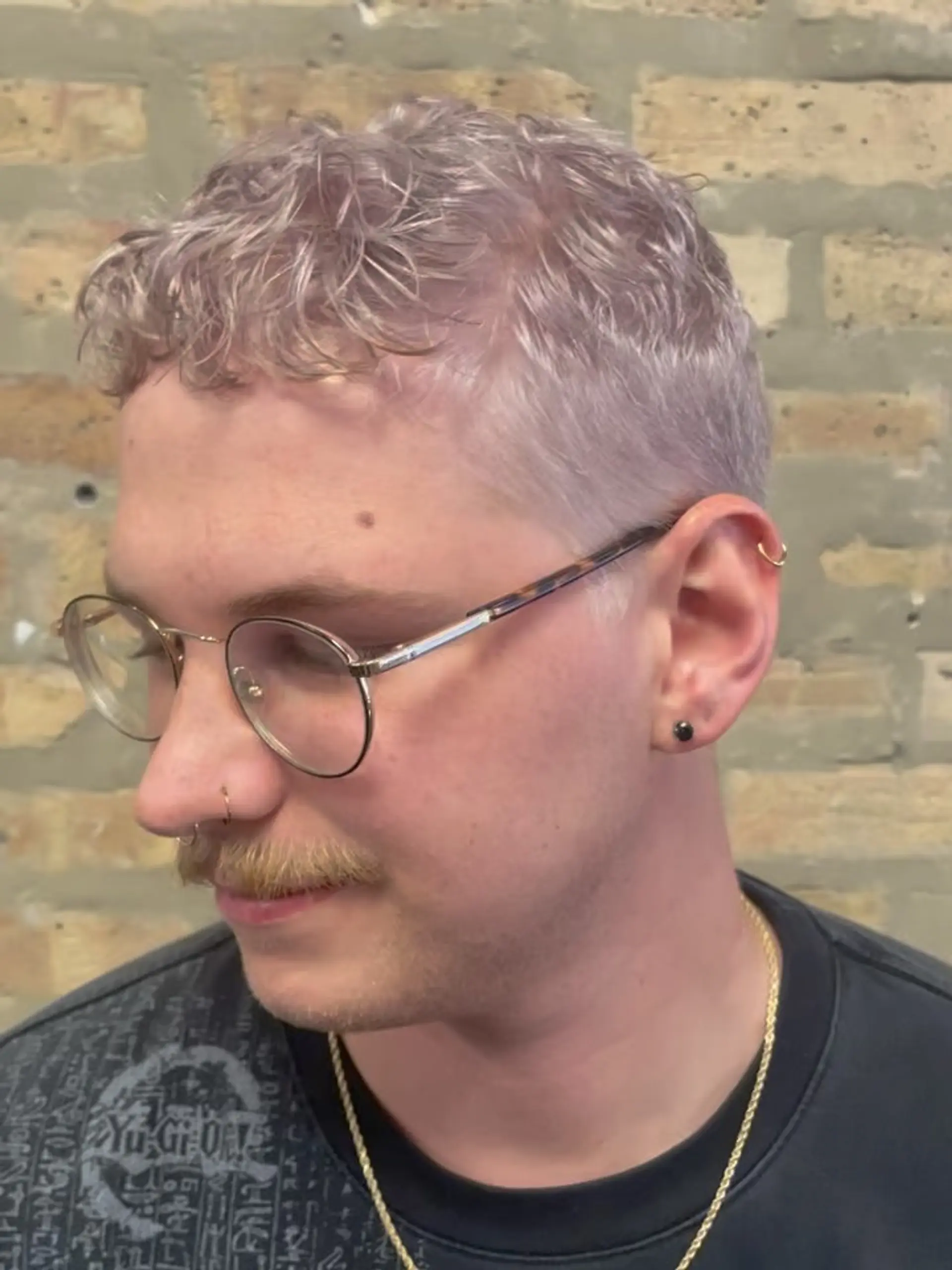 A short textured crop featuring soft wavy bangs and tapered sides, toned to an icy double-violet platinum blonde. 1