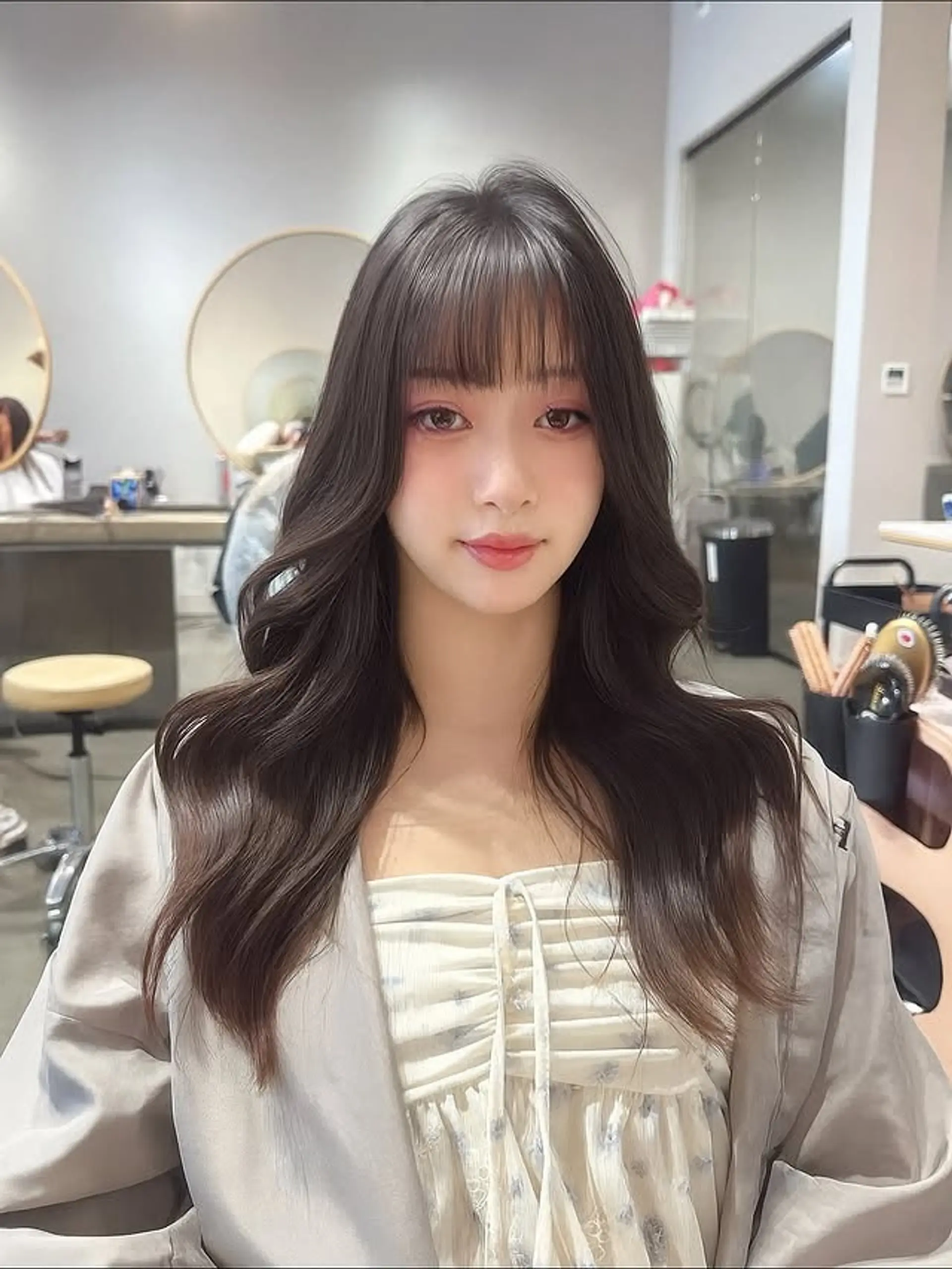 A long, wavy hairstyle with soft, romantic curls and wispy, see-through bangs. 1