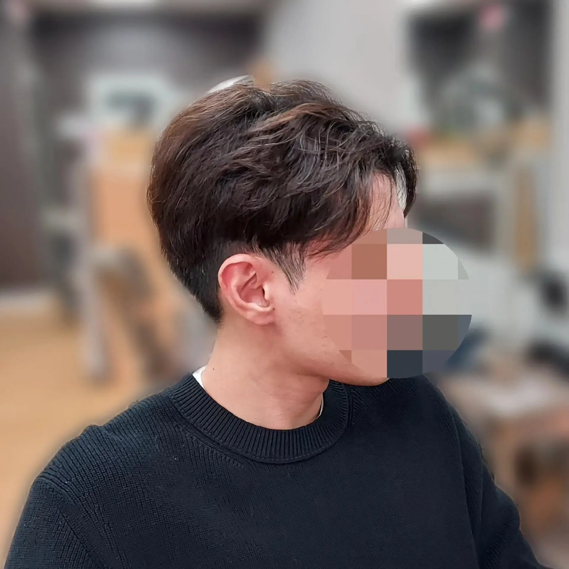 A men's short haircut featuring clean tapered sides and a wavy, volumized top parted into casual curtain bangs. 1