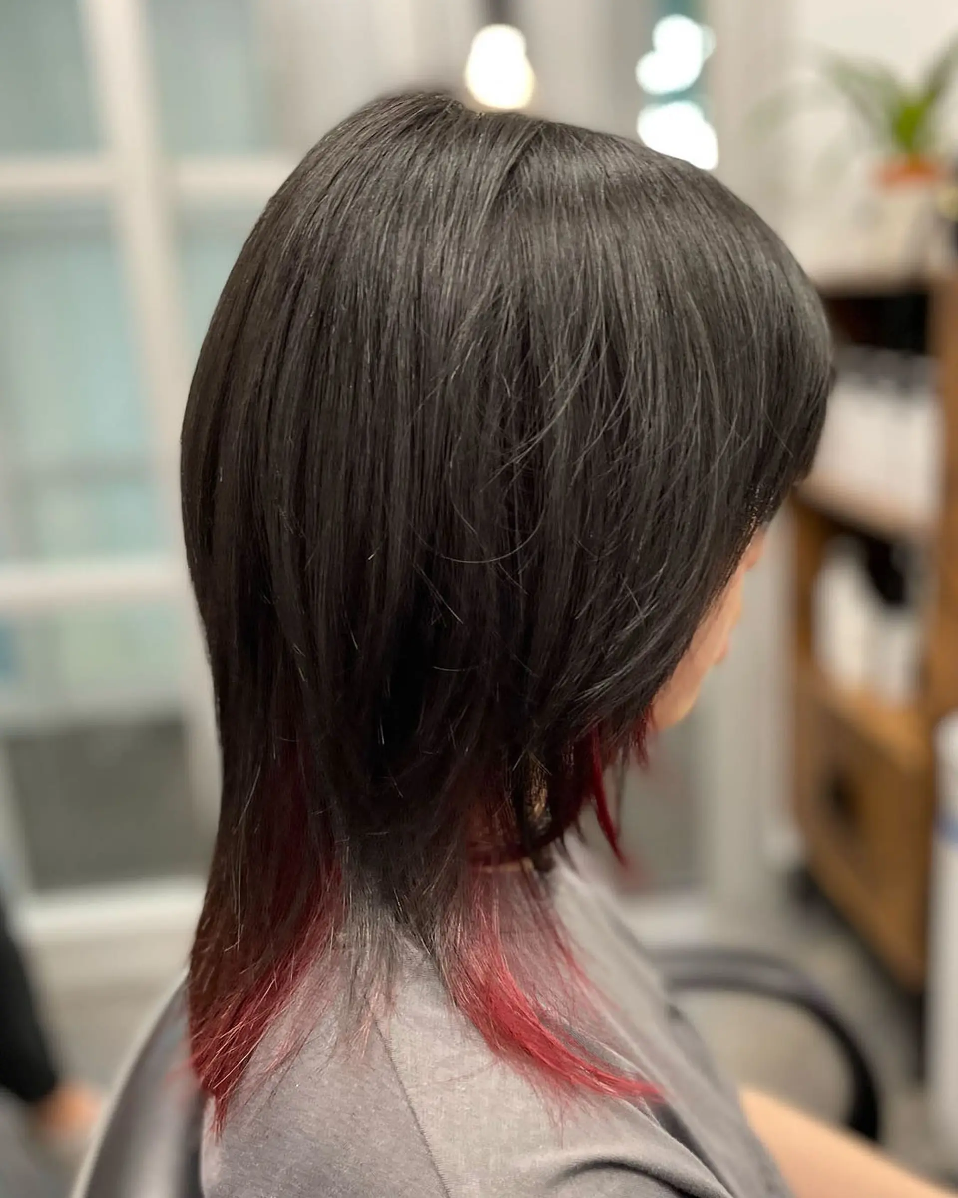 A textured medium-length shag cut with black layers and vibrant red peekaboo accent color. 1