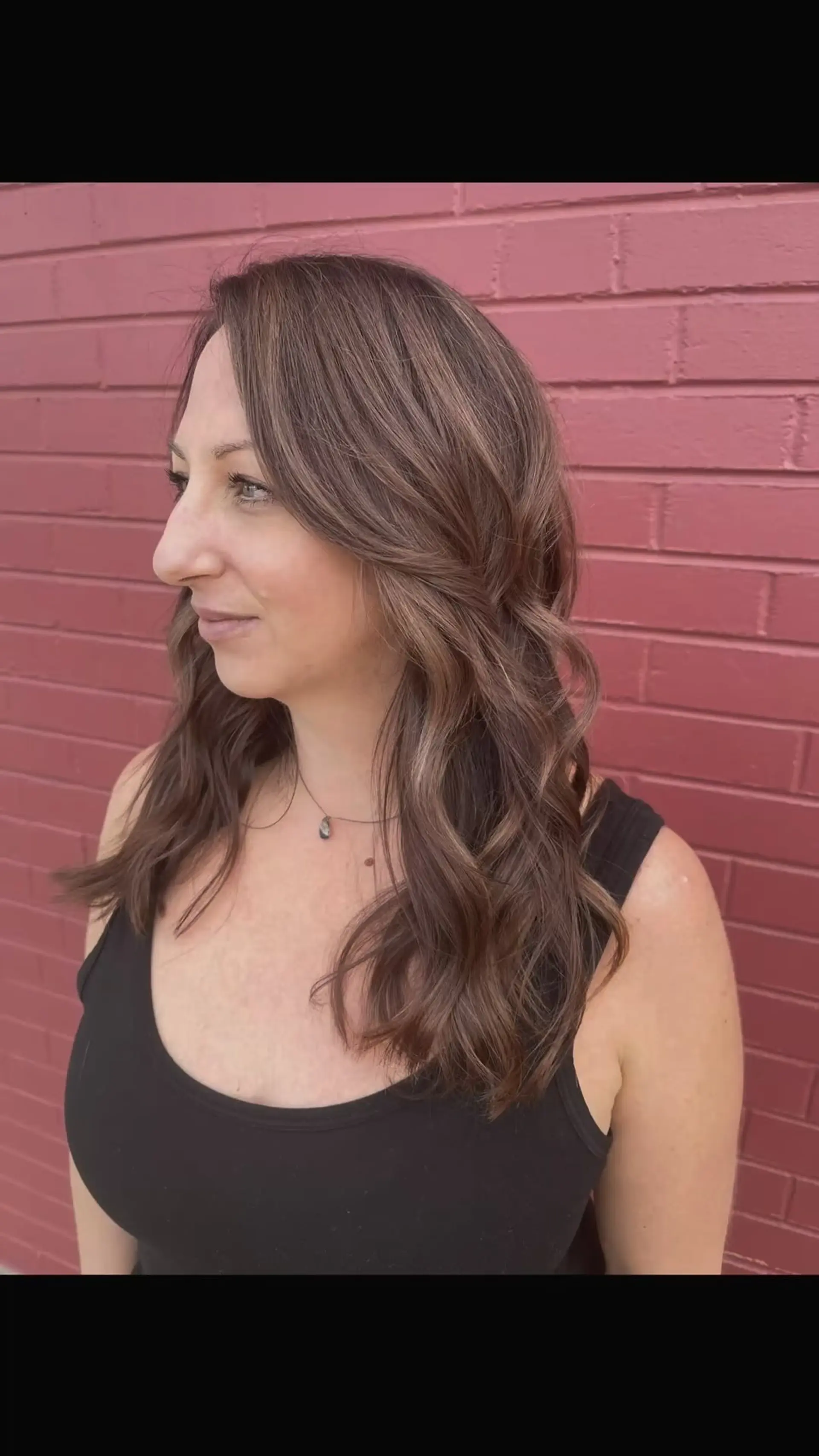 Long mauve-toned brunette hair styled in soft, loose waves with face-framing layers and delicate babylights. 1