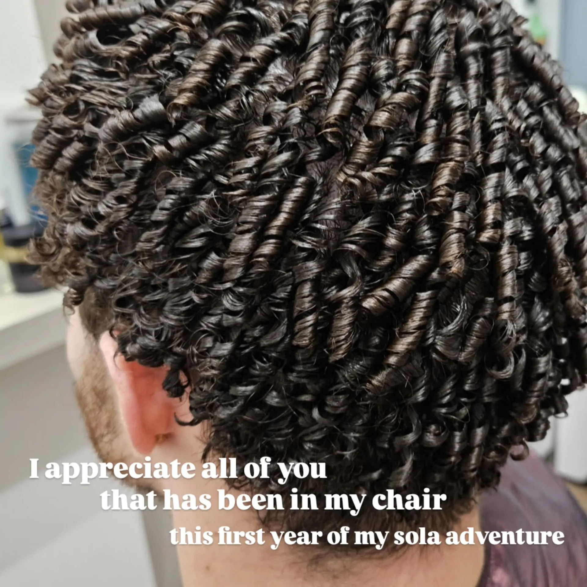 Short dark hair styled into extremely defined, glossy tight spiral ringlets across the entire head. 1