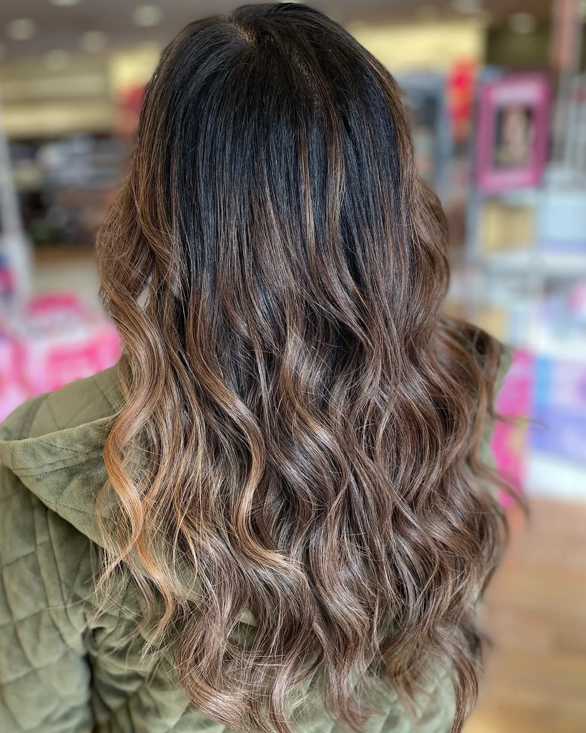 Long dark brunette hair featuring subtle caramel balayage highlights styled in soft, loose waves. 1