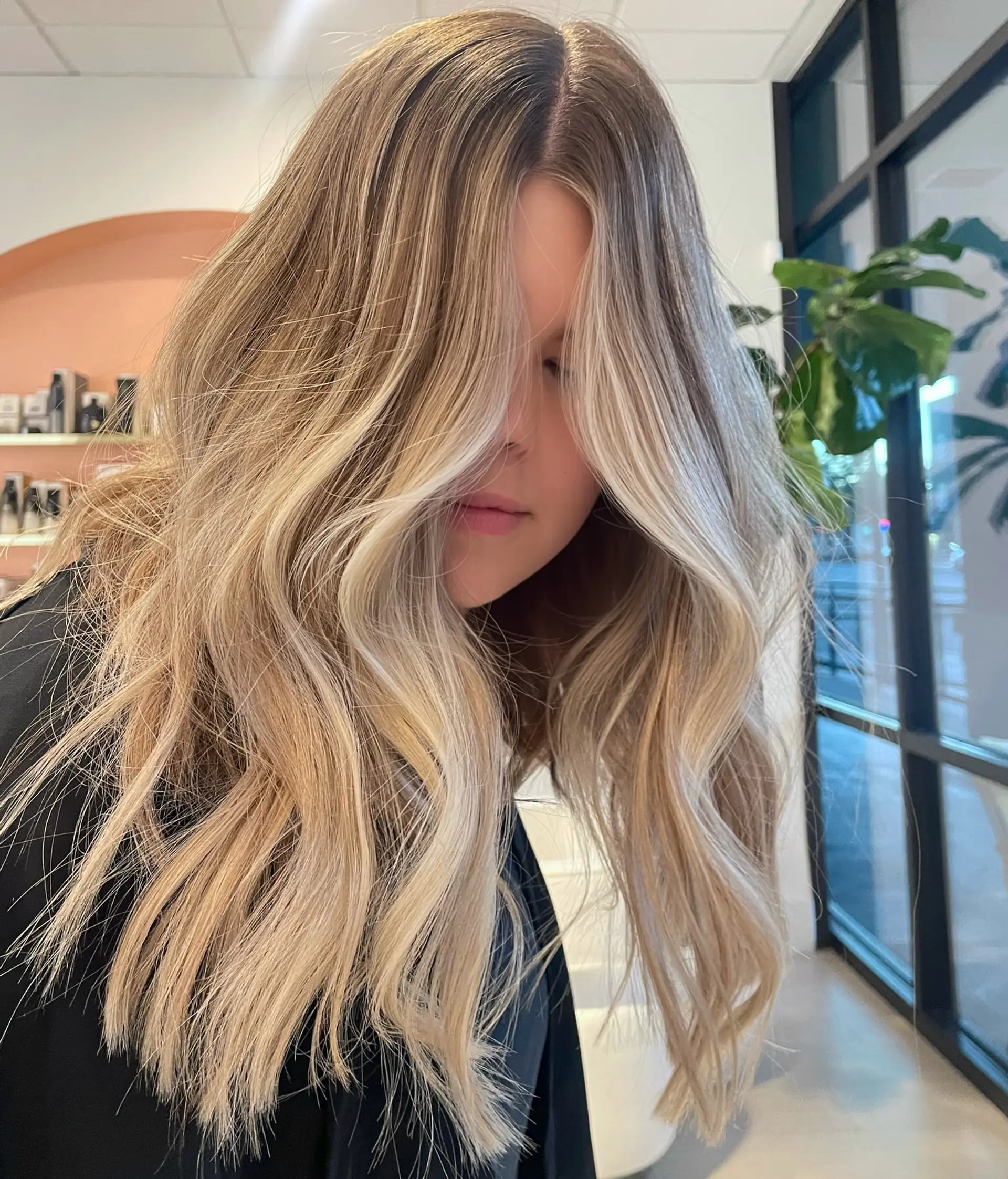 Long lived-in blonde hair styled in soft, undone waves with a blended root and face-framing highlights. 1