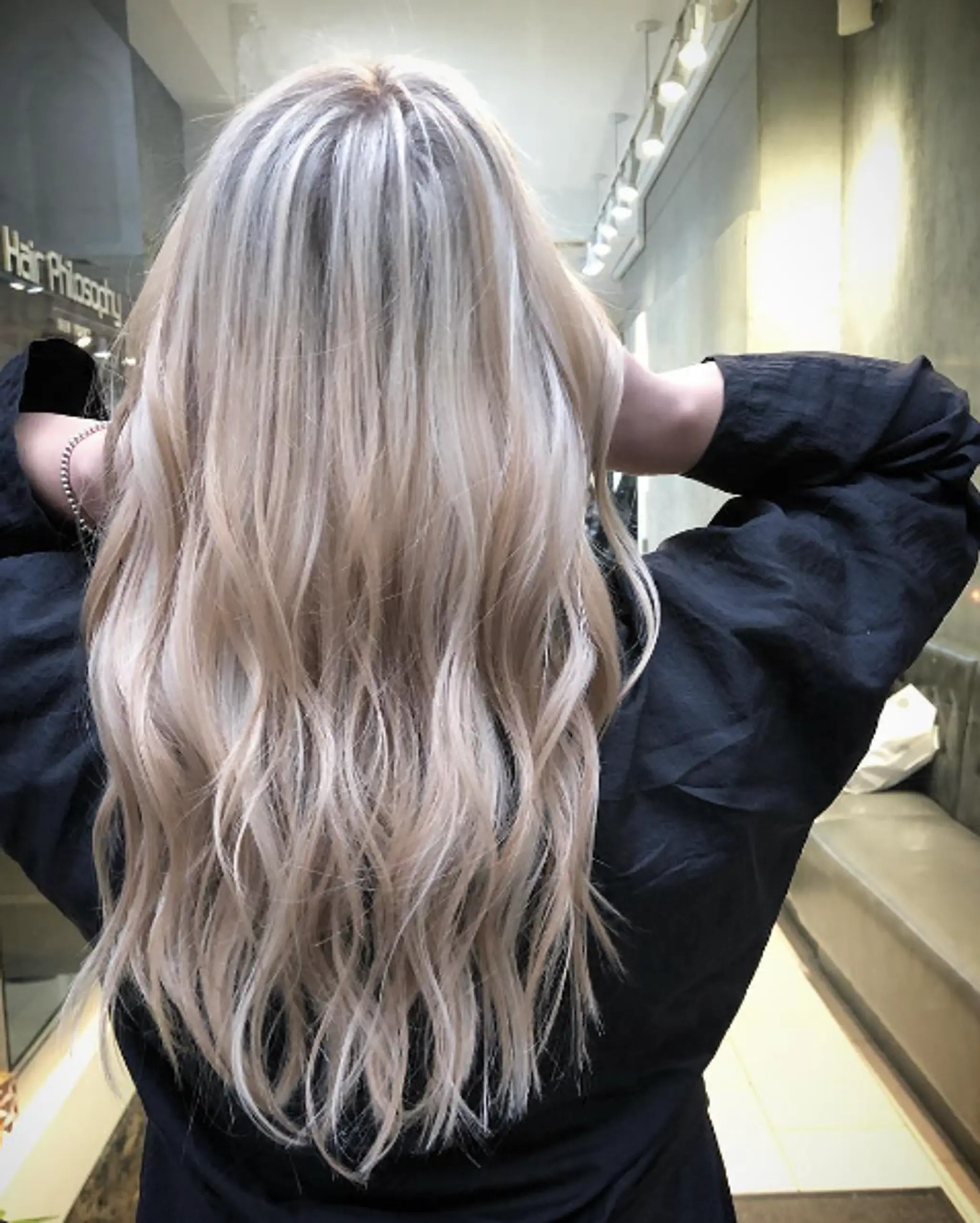 Long, wavy platinum blonde hair with subtle honey highlights, featuring natural waves and soft layers for added volume and a shiny finish.