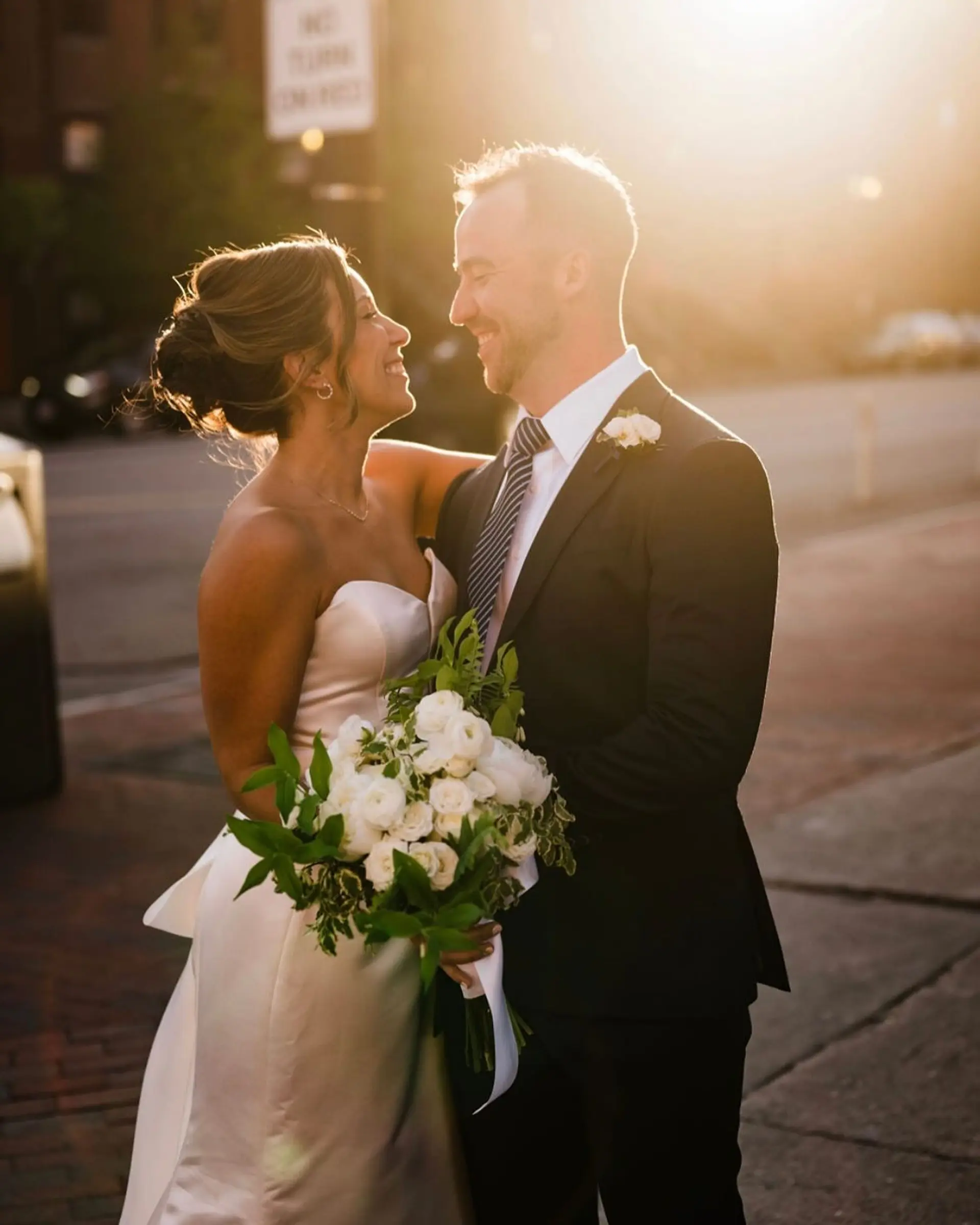 A romantic textured bridal updo styled into an elegant gathered bun with loose, face-framing tendrils. 1