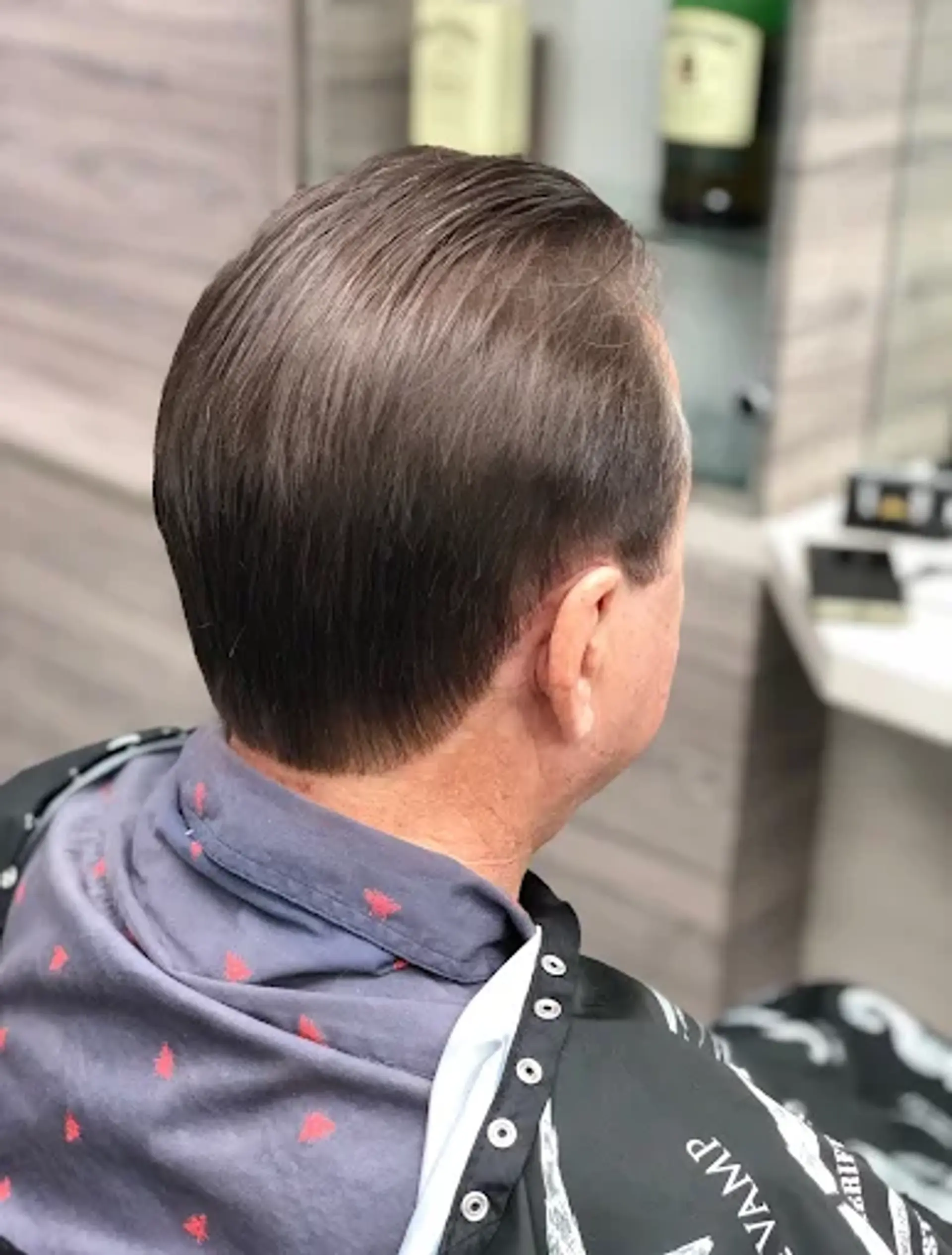 A classic men's haircut with neatly tapered back and sides, and the top smoothly swept backward, creating a clean and professional aesthetic. 1