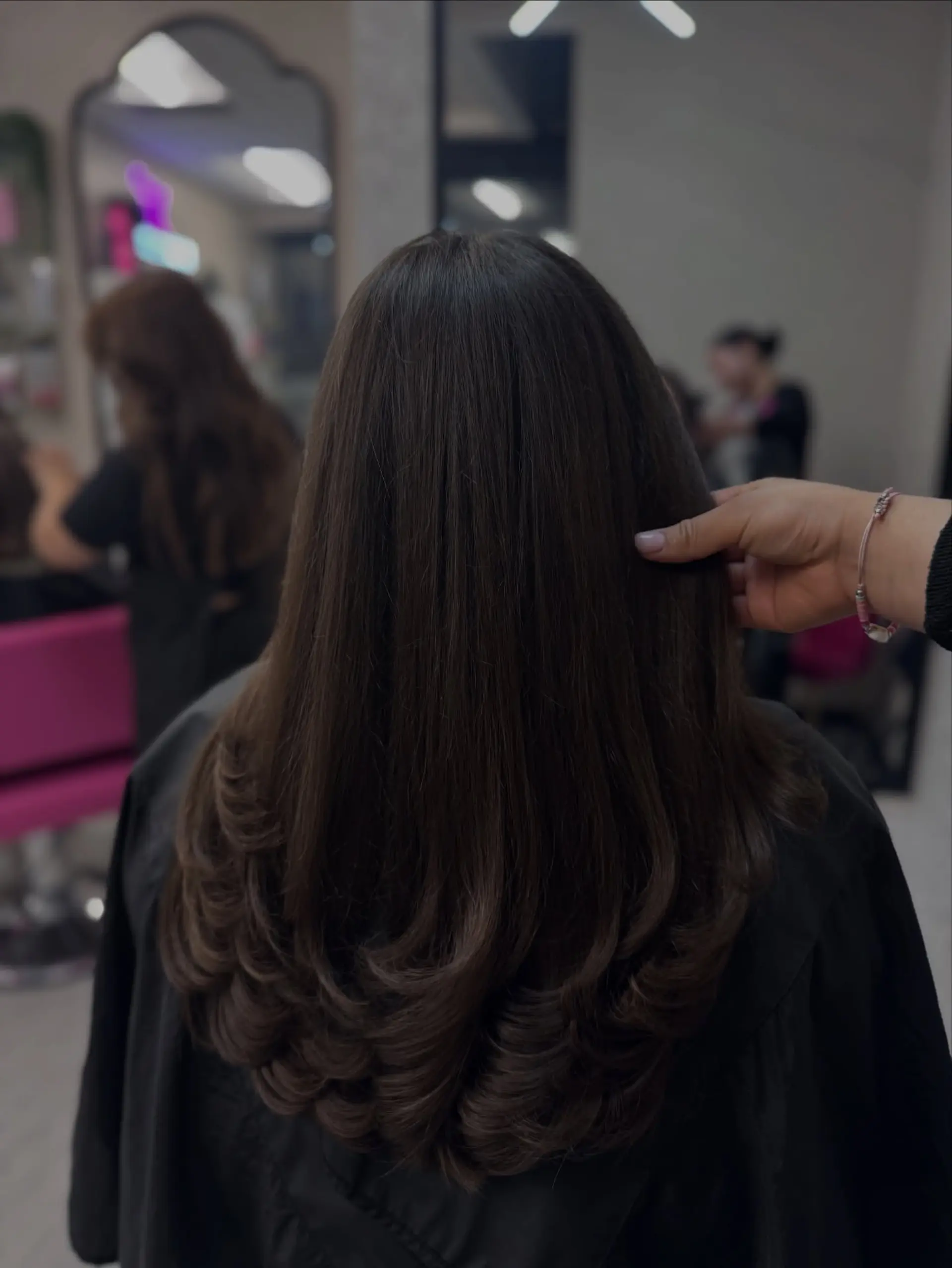 Long dark brown hair cut with soft cascading layers and styled into a voluminous blowout with curled-under ends. 1
