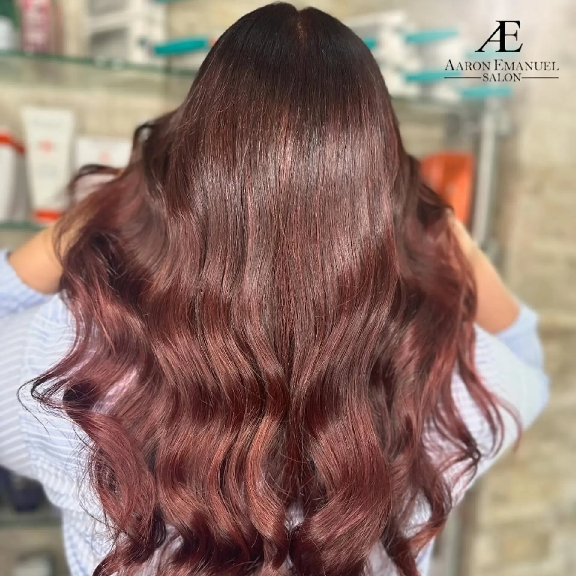 Long wavy hairstyle with a burgundy and auburn blend, featuring soft, romantic waves and a glossy finish. 1