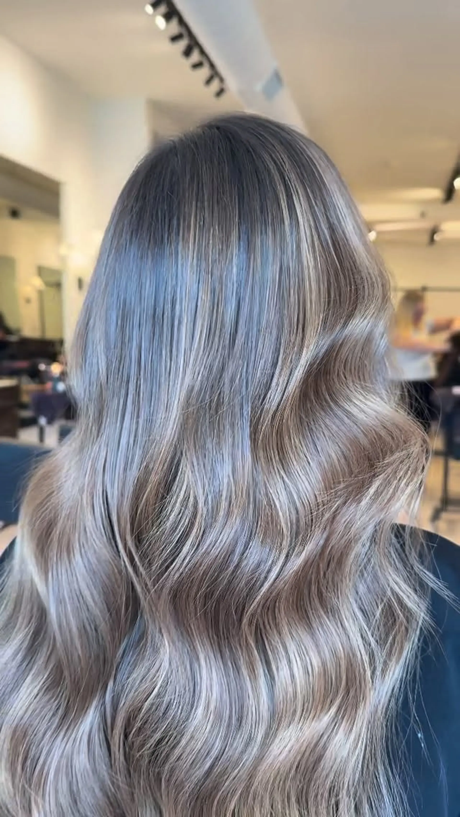Long cool-toned dimensional blonde hair styled into smooth, flowing salon waves. 1