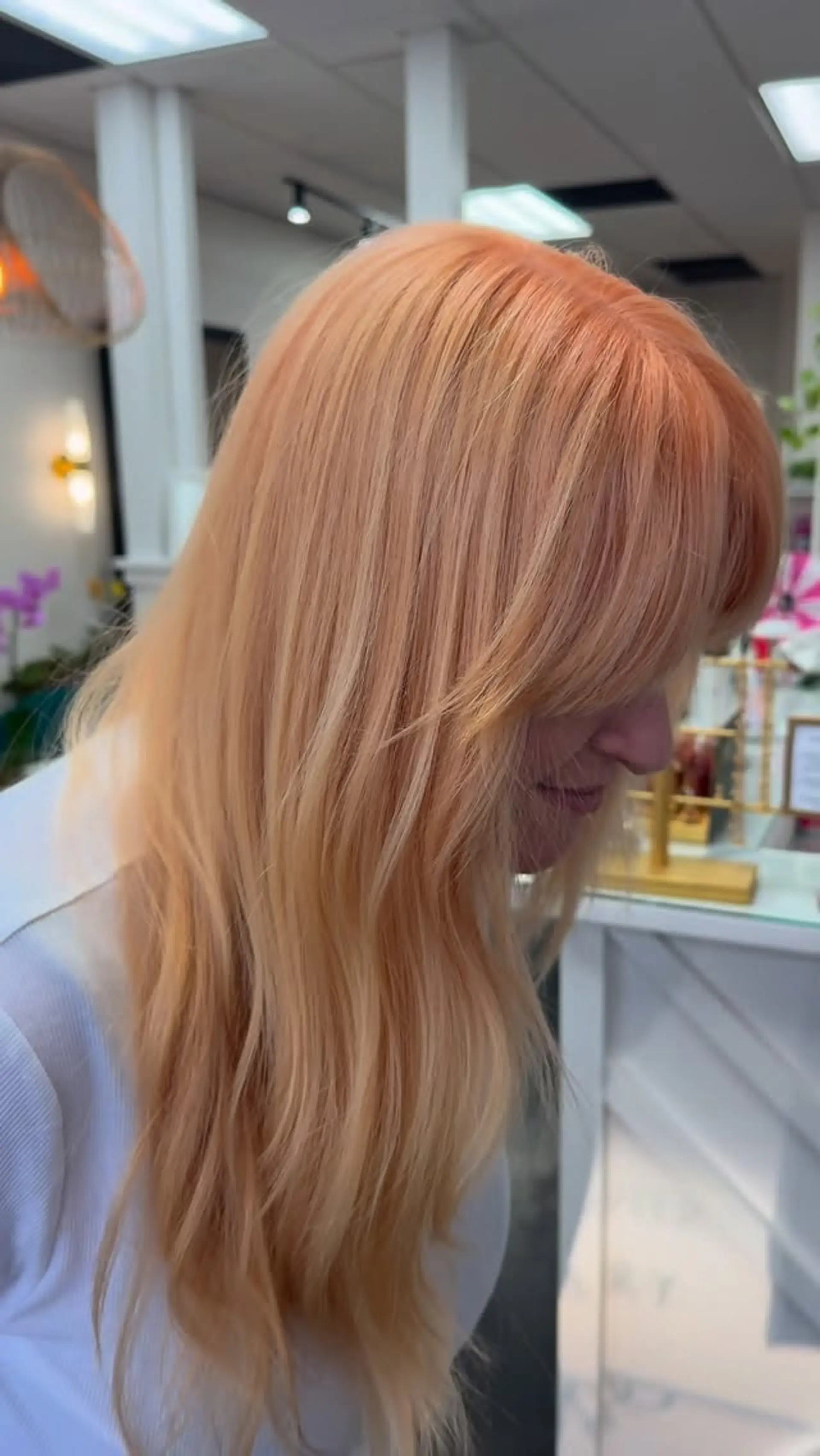 Pastel peach-toned long blonde hair styled with soft, natural texture and full fringe bangs. 1