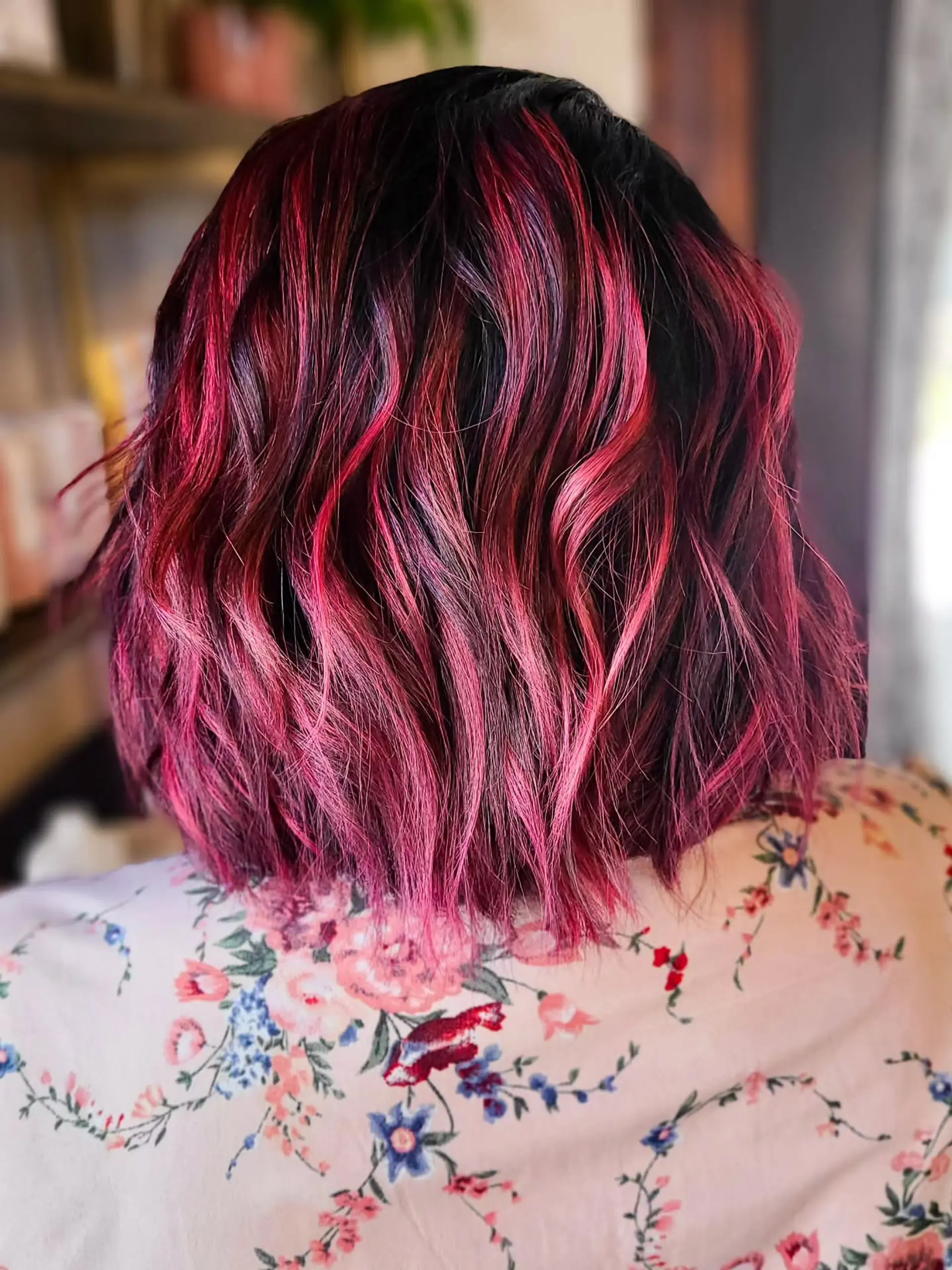 A trendy medium-length wavy bob, showcasing dynamic magenta and pink highlights over a dark base, styled with soft, natural waves for a playful yet sophisticated look. 1