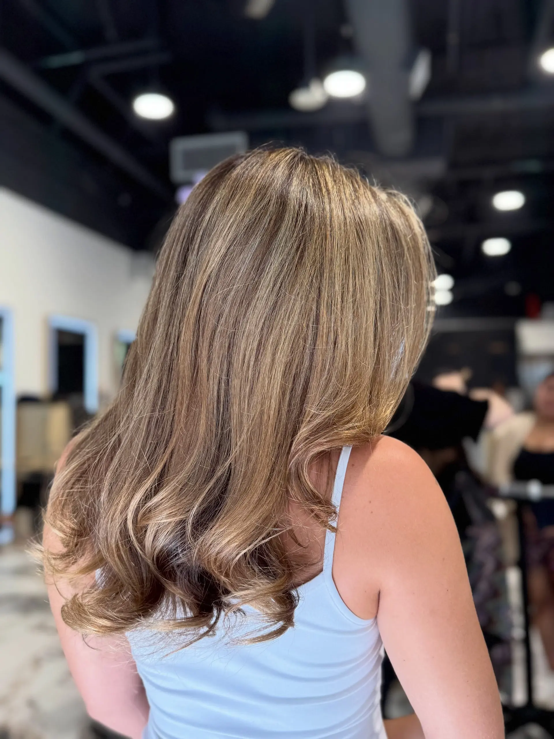 Long hair featuring warm blonde partial highlights styled in a sleek, bouncy blowout with soft curls at the ends. 1
