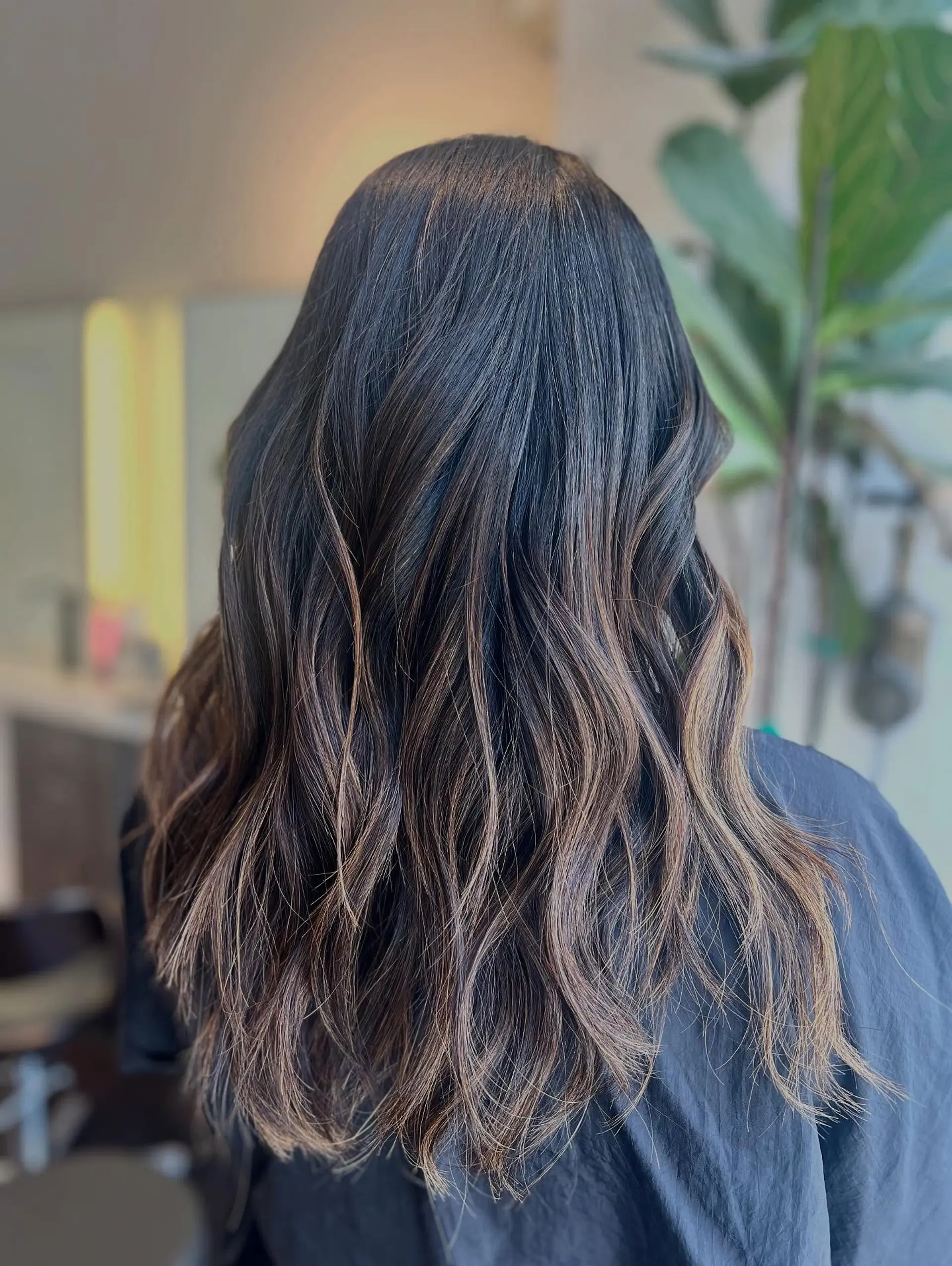 Long layered brunette hair styled into effortless, soft waves with subtle caramel balayage dimension. 1