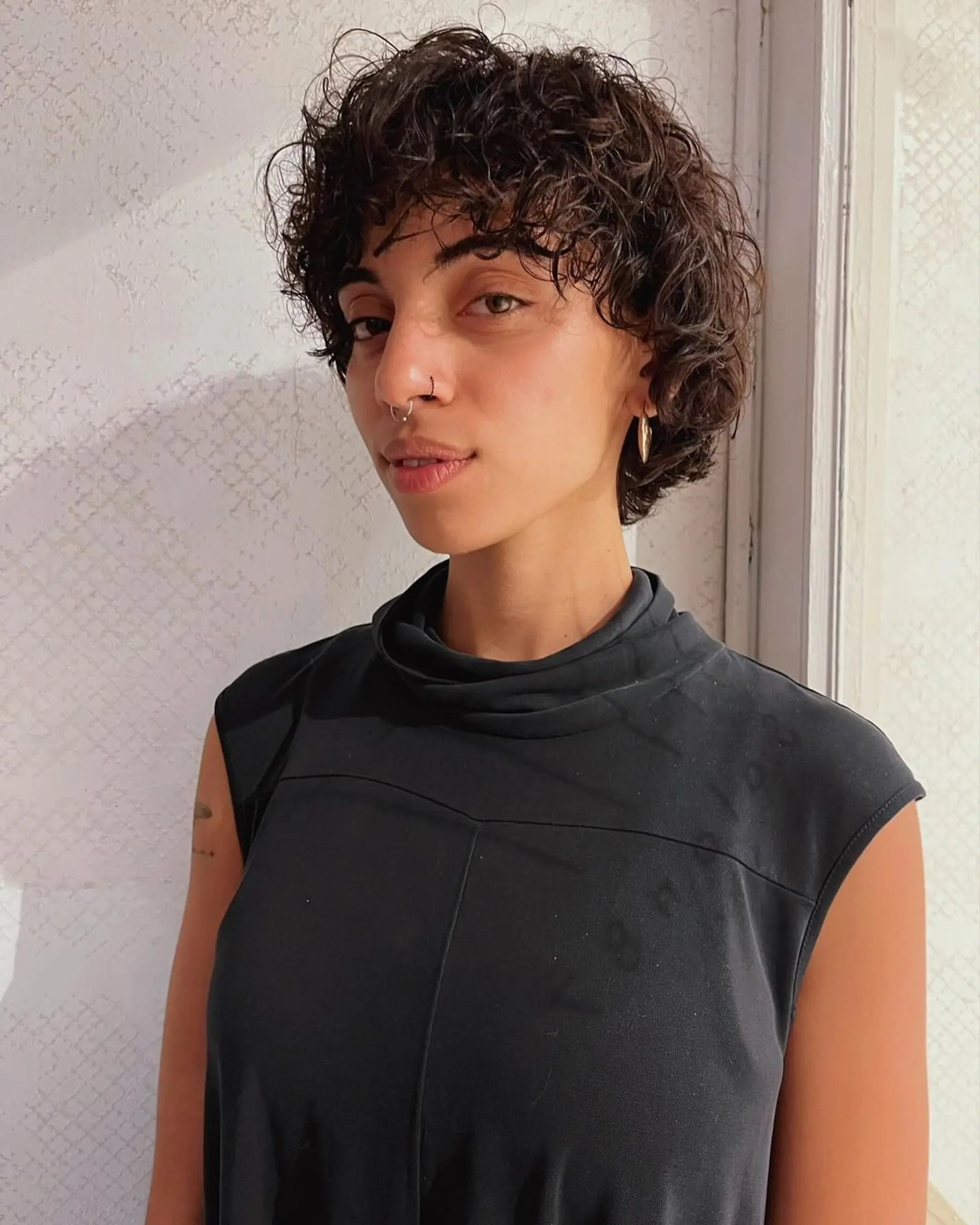 Short, dark brown curly hair with a curled fringe and volume at the crown, highlighting natural texture and relaxed curls. 1