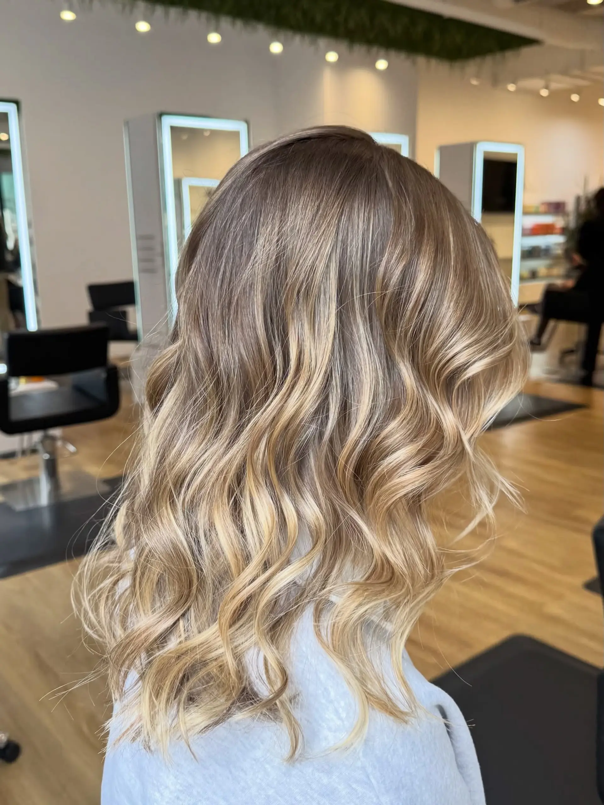 Lived-in blonde balayage with soft, loose waves and dimensional highlights blending seamlessly from darker roots. 1