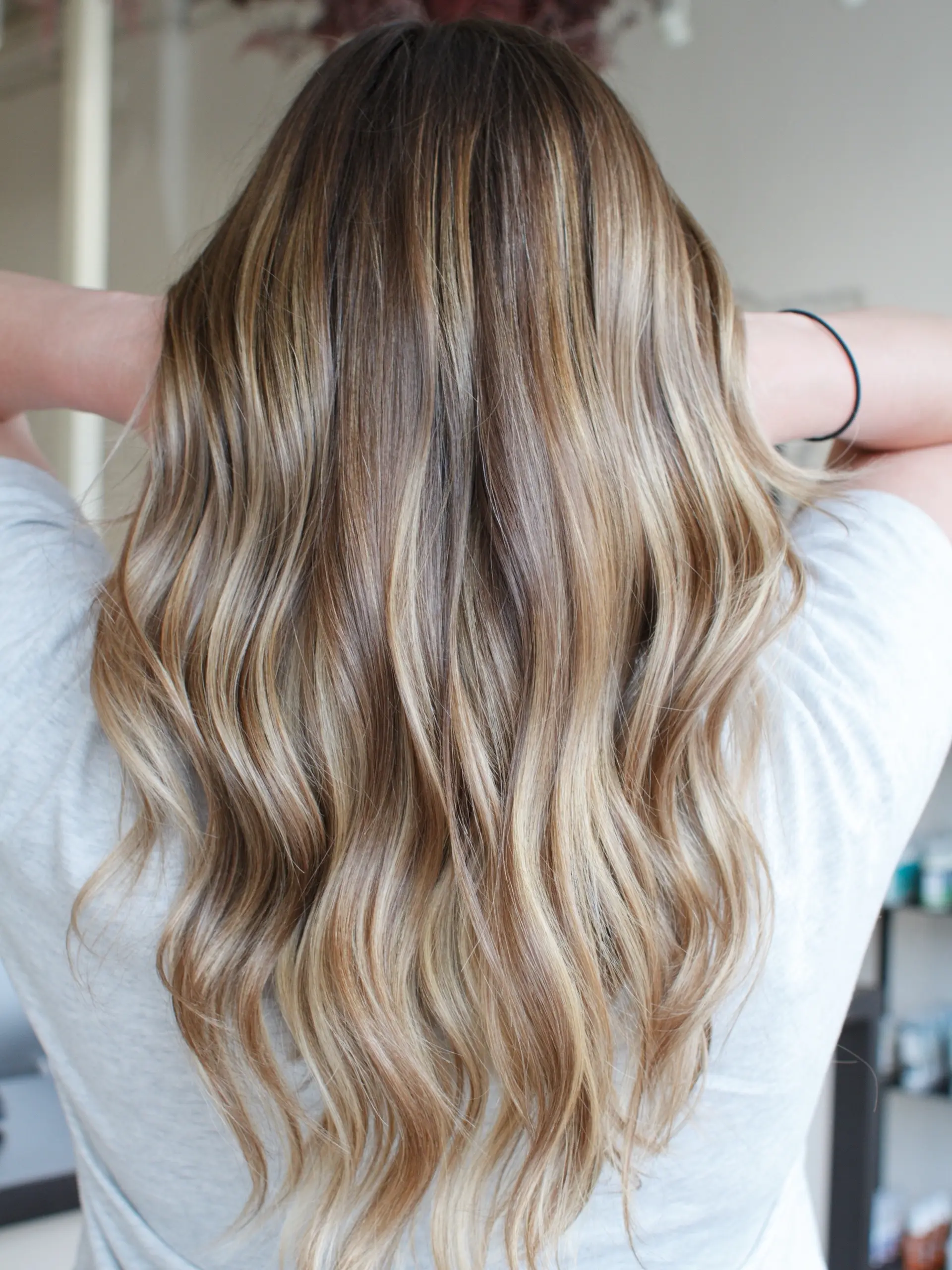 Long warm dimensional blonde hair styled in soft, cascading waves. 1