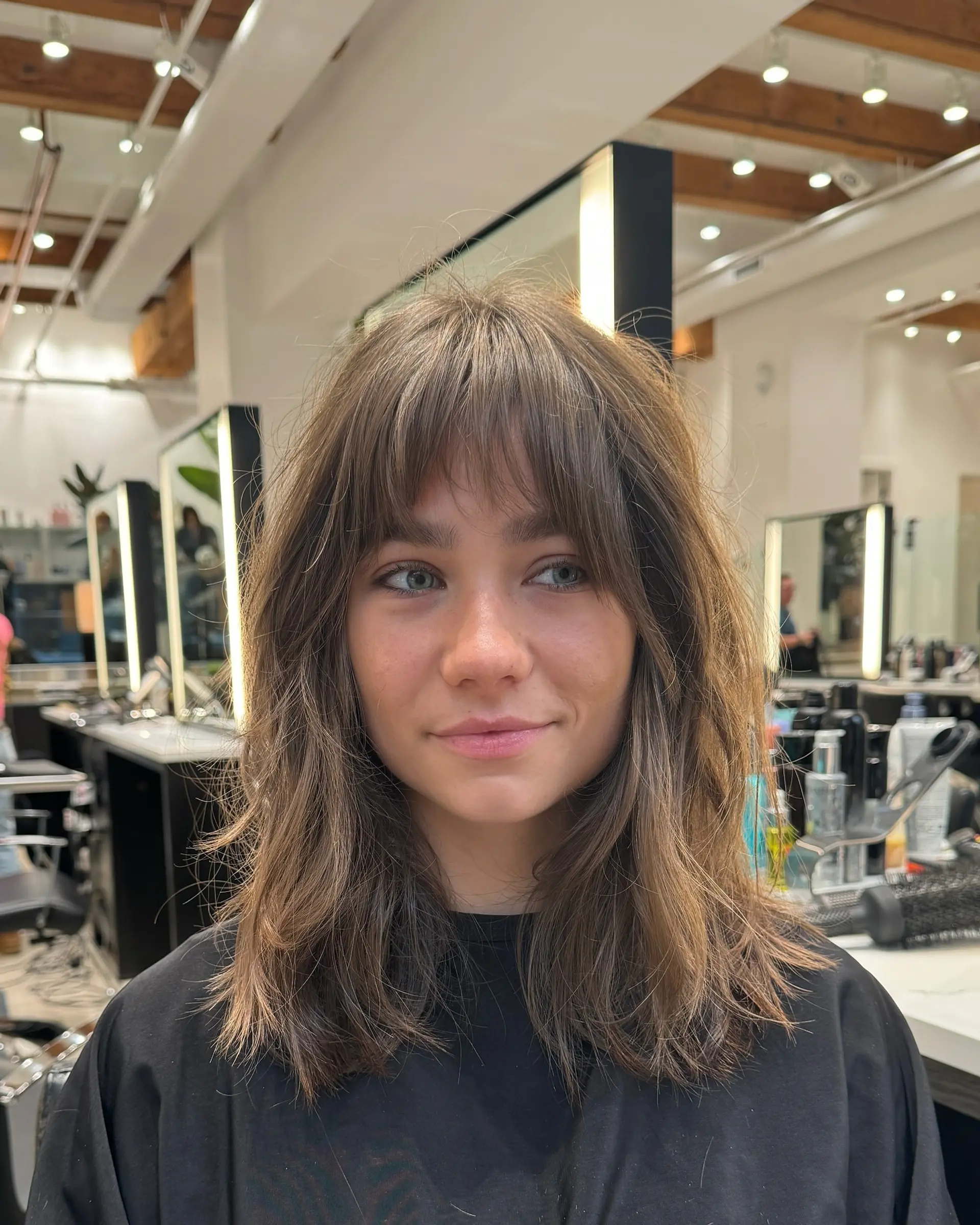 A medium-length shag haircut with face-framing layers and curtain bangs. 1