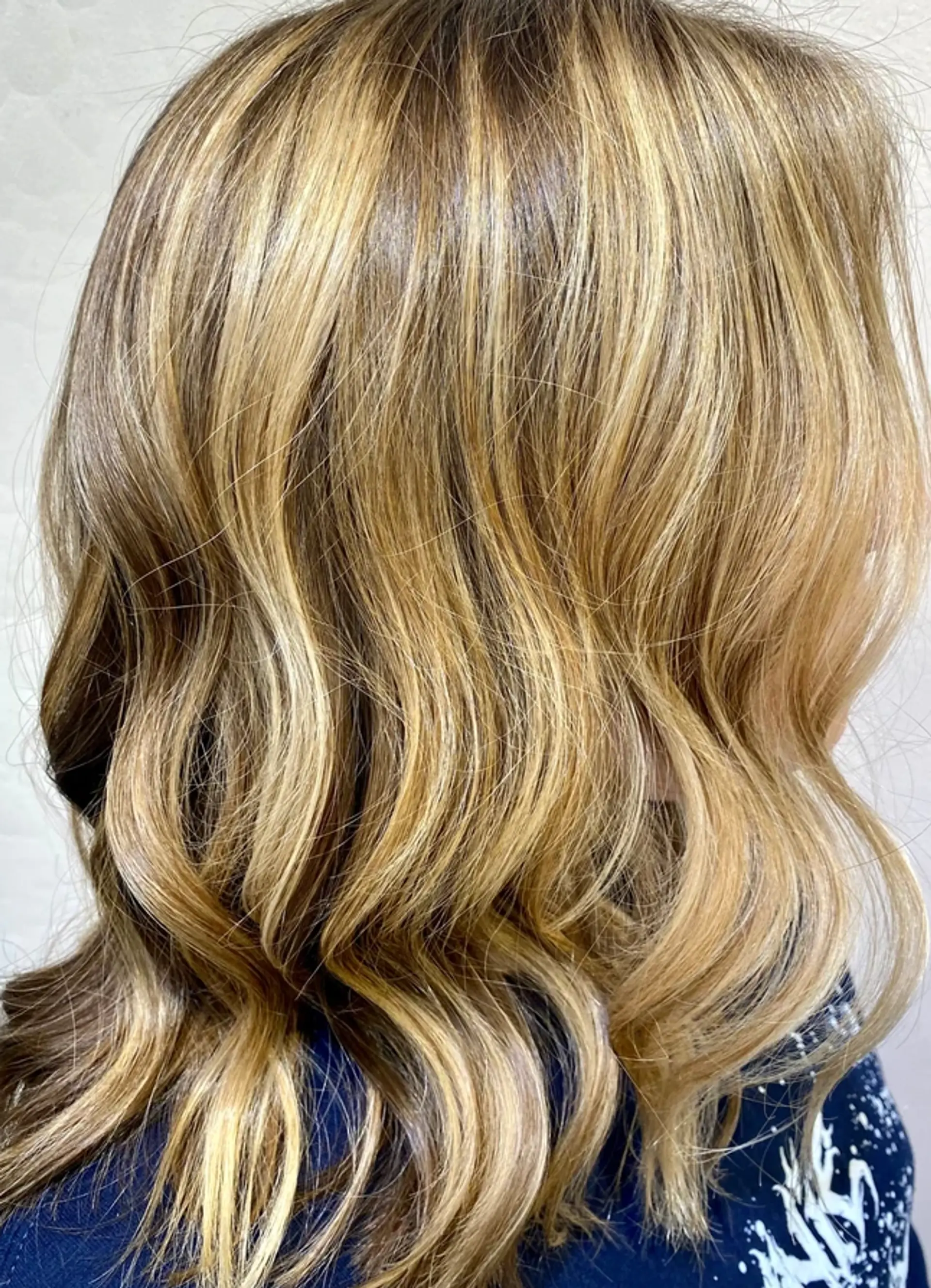Long wavy hairstyle with golden blonde and honey tones, natural shine, and layered cut. 1