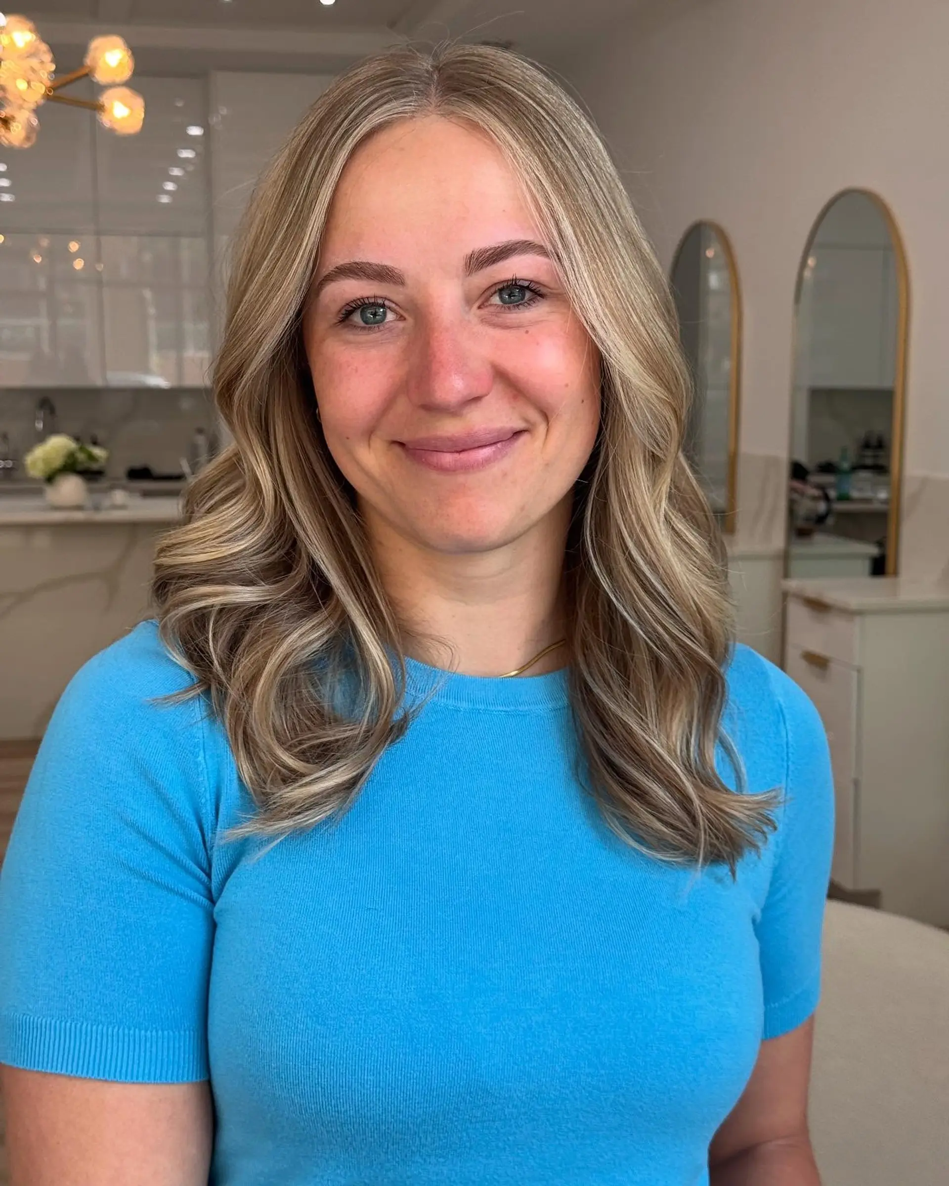 Medium-length dimensional bright blonde hair styled with soft, loose waves and face-framing highlights. 1