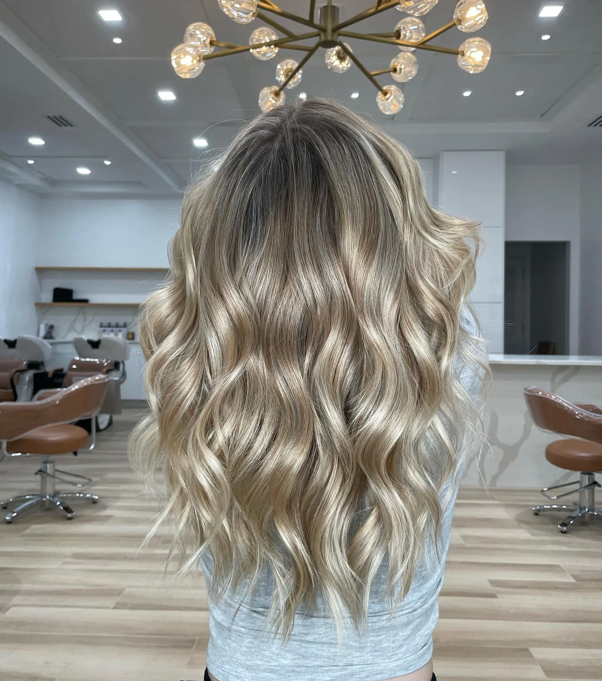 Long hair featuring a seamless lived-in blonde balayage styled with soft, cascading waves. 1