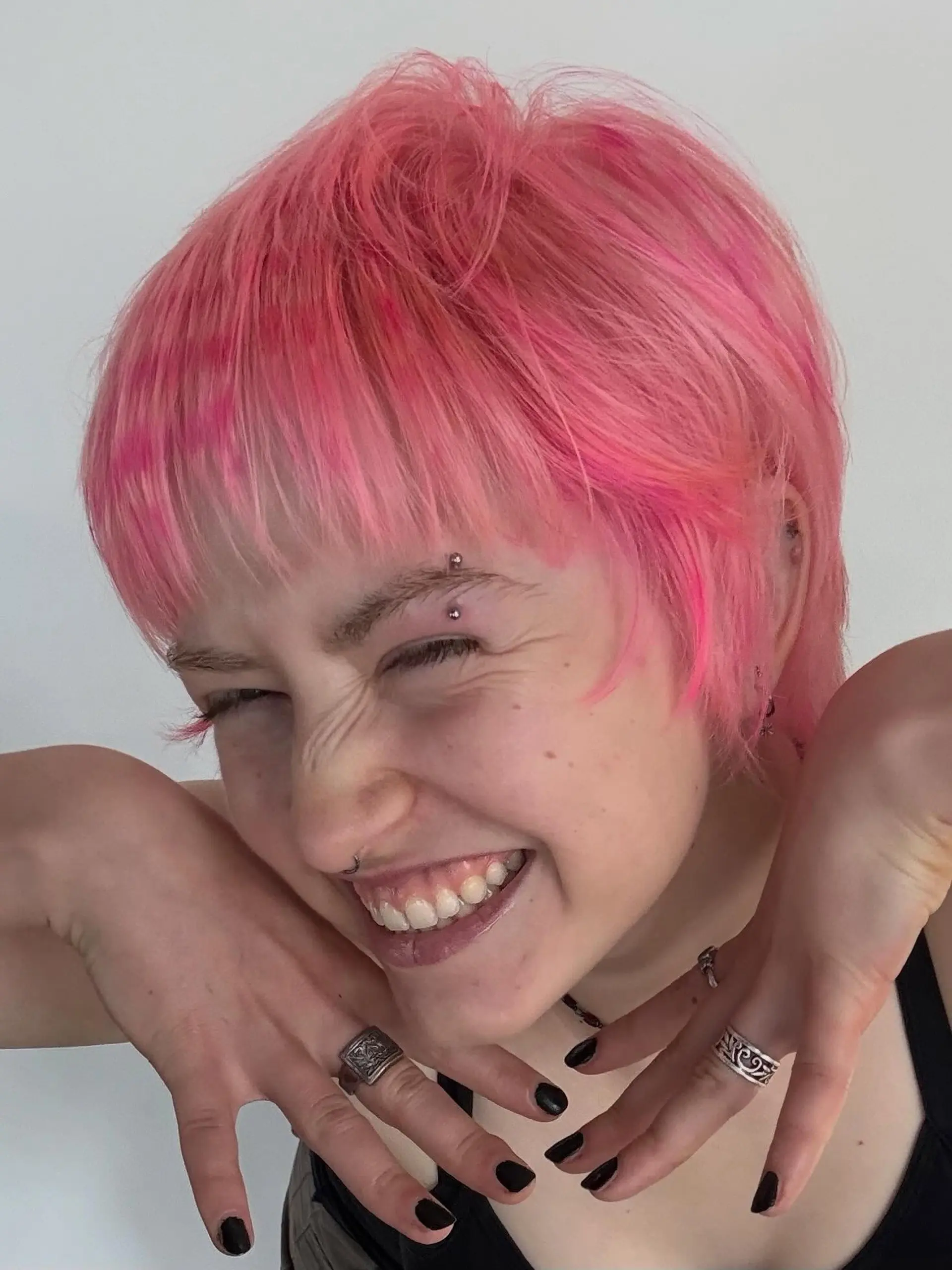 A textured short pixie cut dyed vibrant bubblegum pink with piecey micro-bangs and subtle darker pink accents. 1