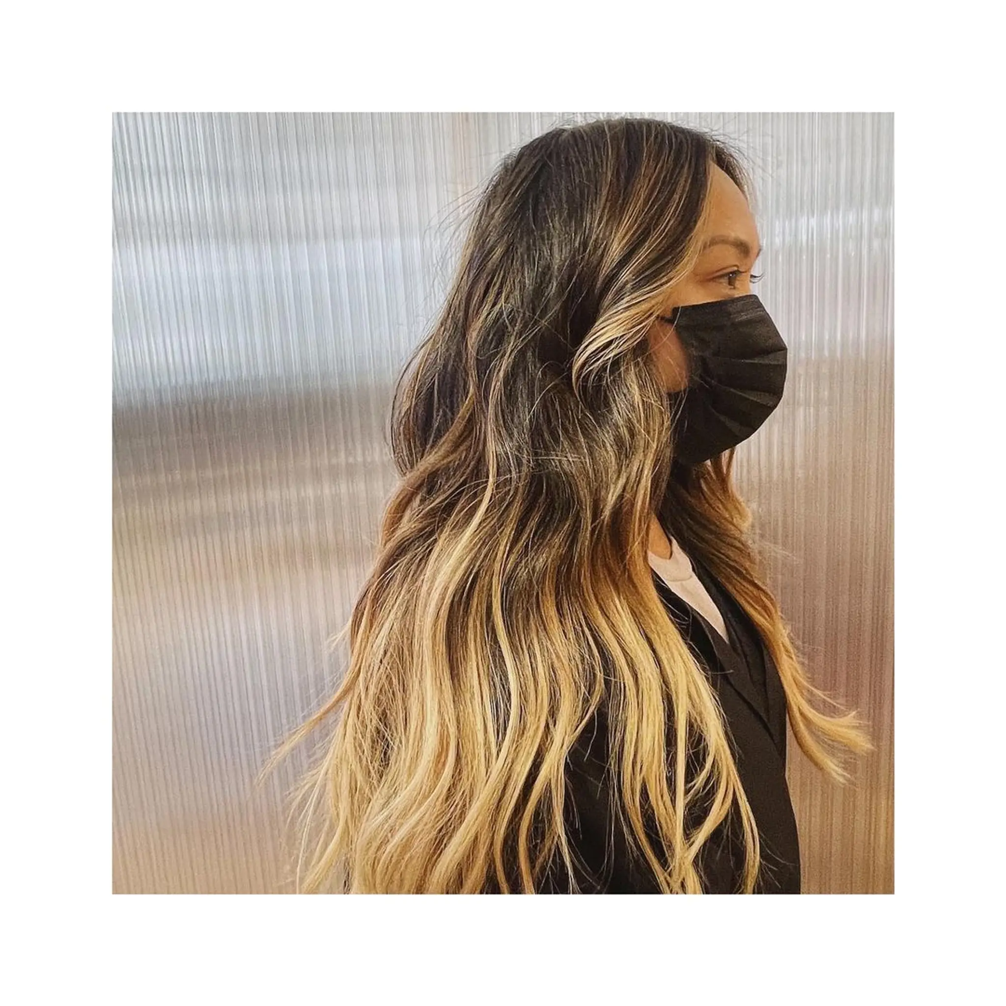 Very long, wavy hair with an ombre effect transitioning from dark brown roots to honey blonde and golden blonde tips, characterized by natural waves and lush volume.