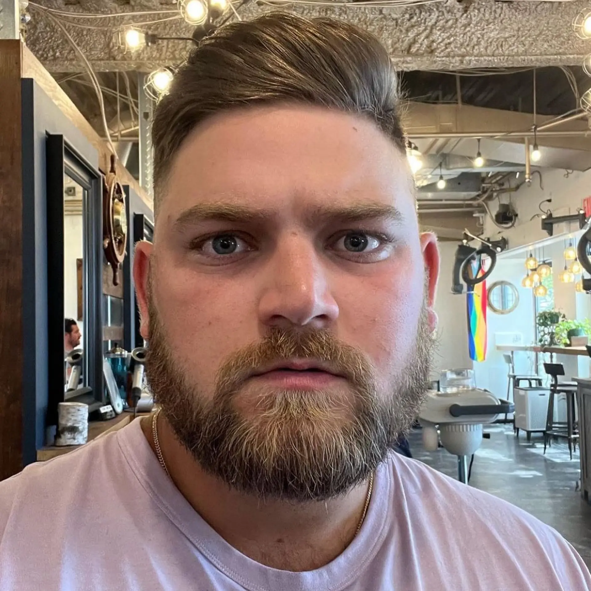A sharp men's pompadour fade cut styled smoothly to the side, complemented by a full, sculpted beard. 1